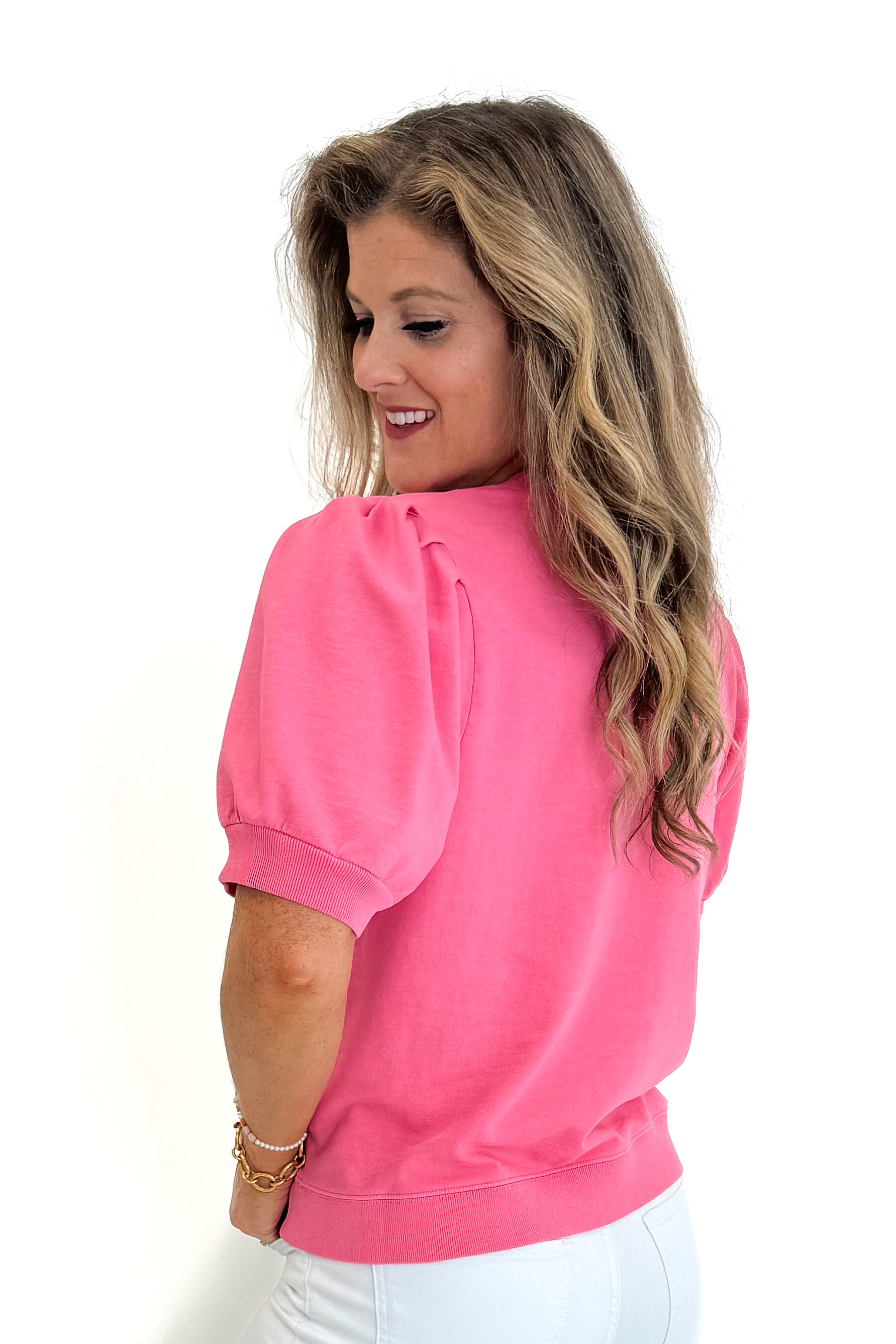 Side view of woman wearing Swagger Boutique’s Pink Puff Short Sleeve Sweatshirt with jeans against white studio background.