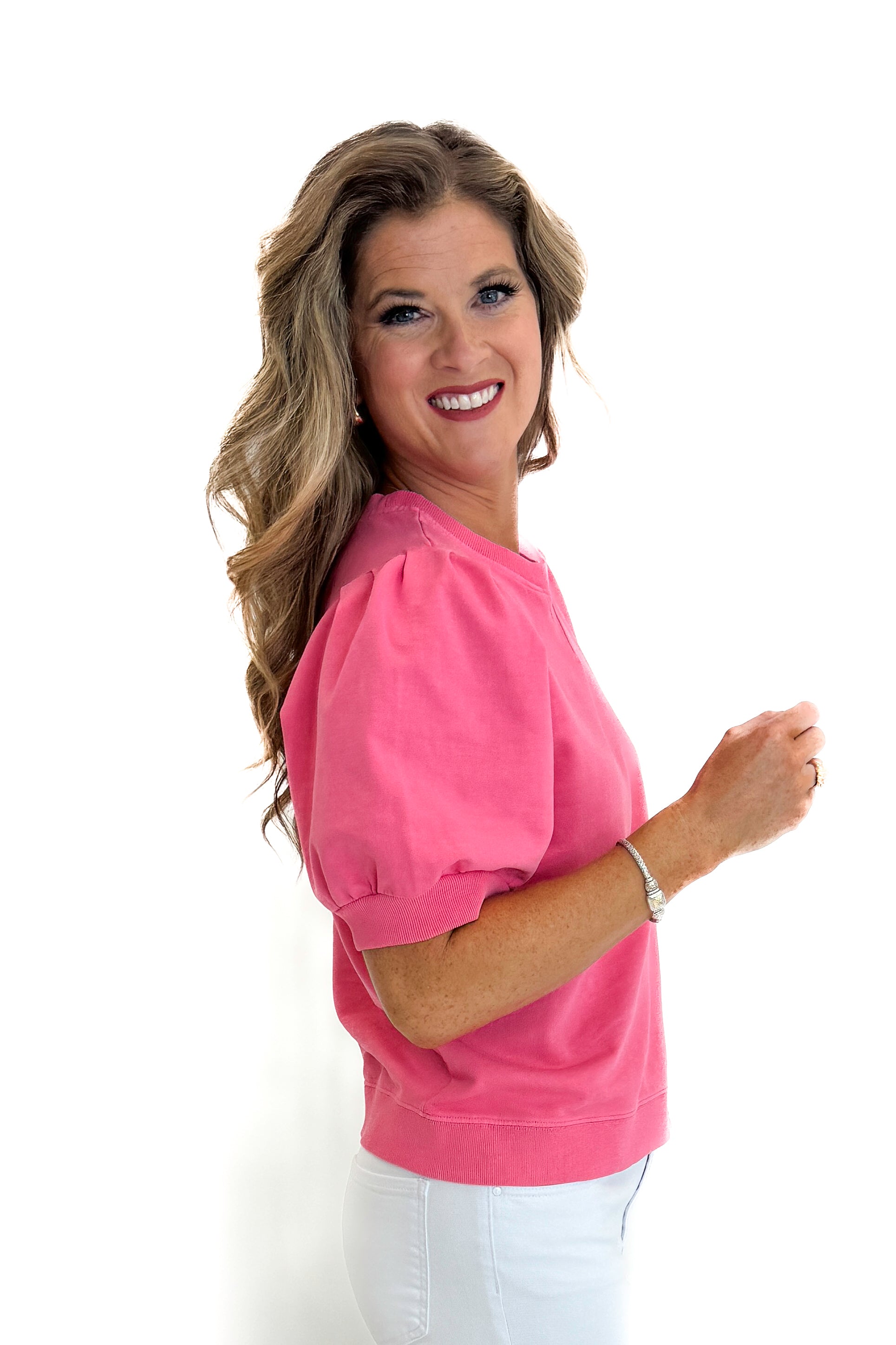 Side view of woman wearing Swagger Boutique’s Pink Puff Short Sleeve Sweatshirt with jeans against white studio background.