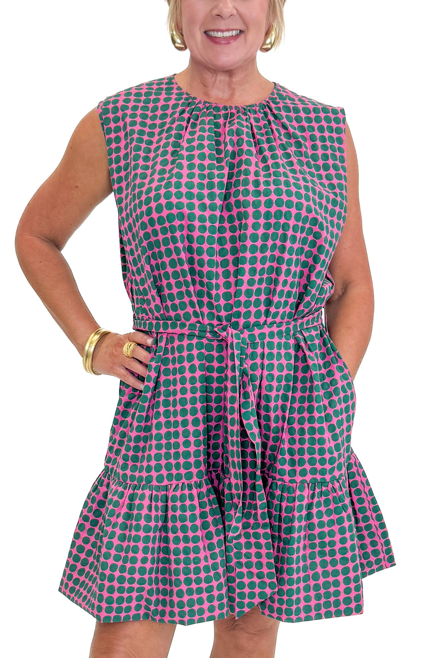 Front detail view of woman wearing Swagger Boutiqueβs Pink & Green Polka Dot Mini Dress with sandals against white studio background.