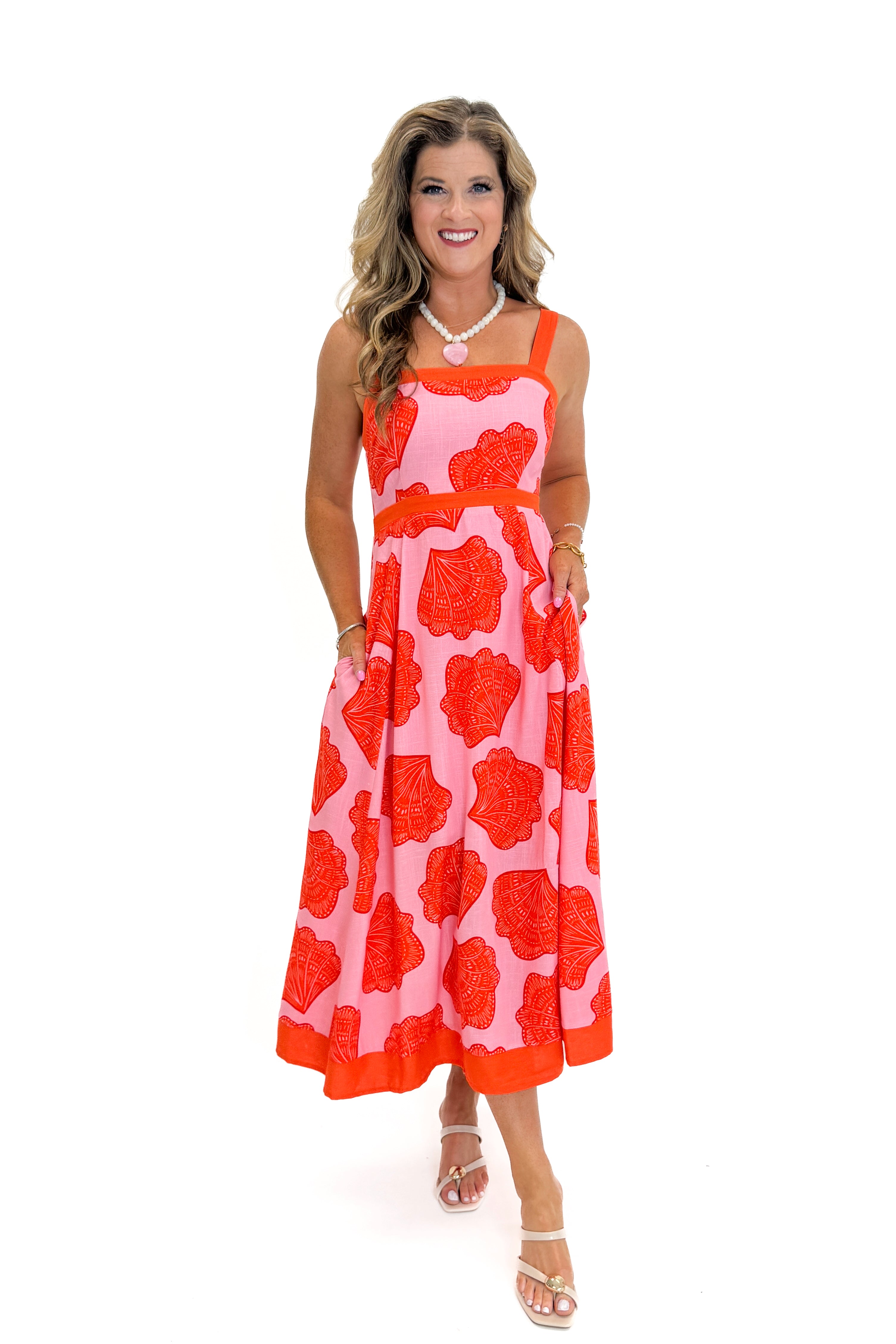 Front view of woman wearing Swagger Boutiqueβs Pink & Orange Printed Midi Dress by Entro with sandals against white studio background.