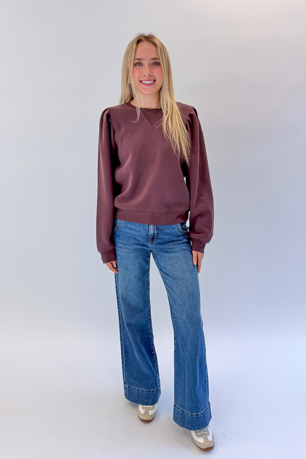 Front view of woman wearing Swagger Boutique’s Plum Puff Sleeve Sweatshirt with jeans against white studio background.