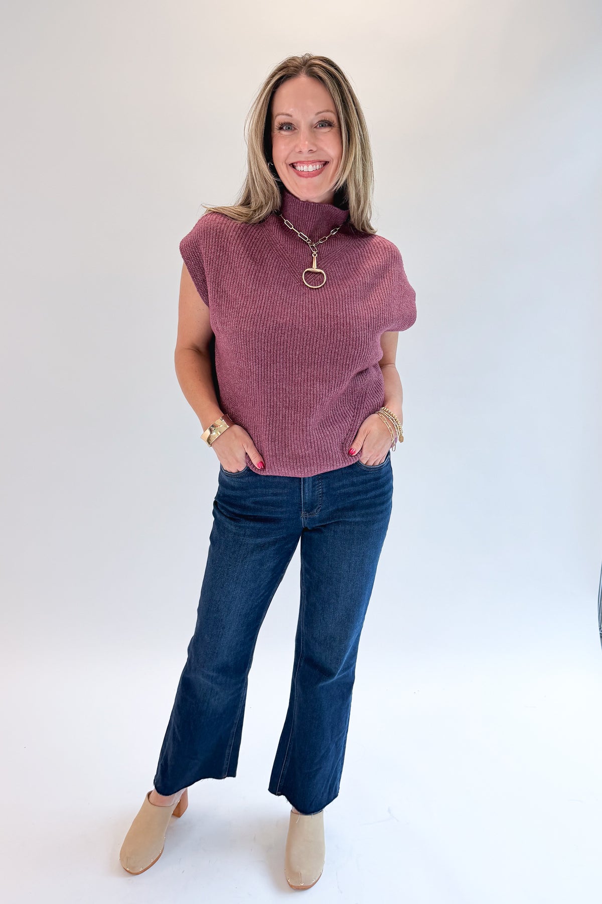 Front view of woman wearing Swagger Boutique’s Plum Sleeveless Mock Neck Sweater with jeans against white studio background.