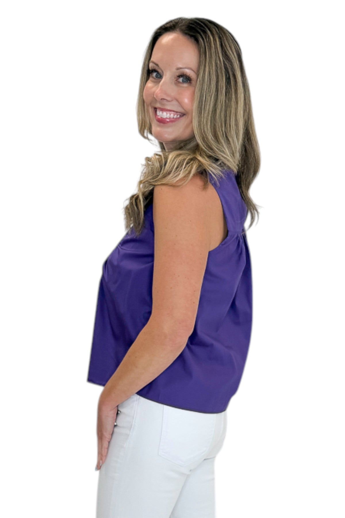 Side view of woman wearing Swagger Boutique’s Purple Ruffle Tank with jeans against white studio background.