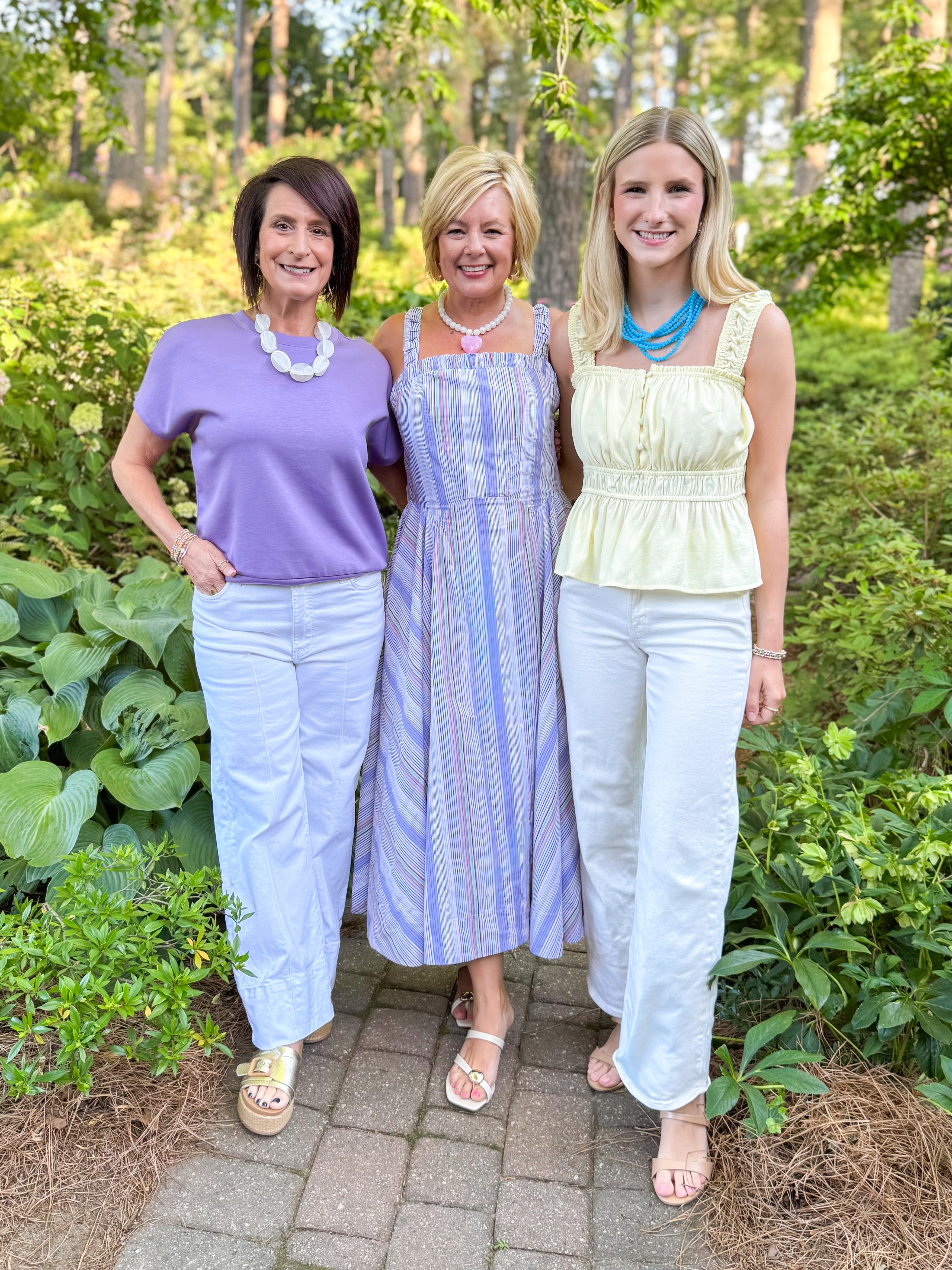 Front view of woman wearing Swagger Boutique’s Purple Short Sleeve Banded Top with jeans and two other women standing outside.