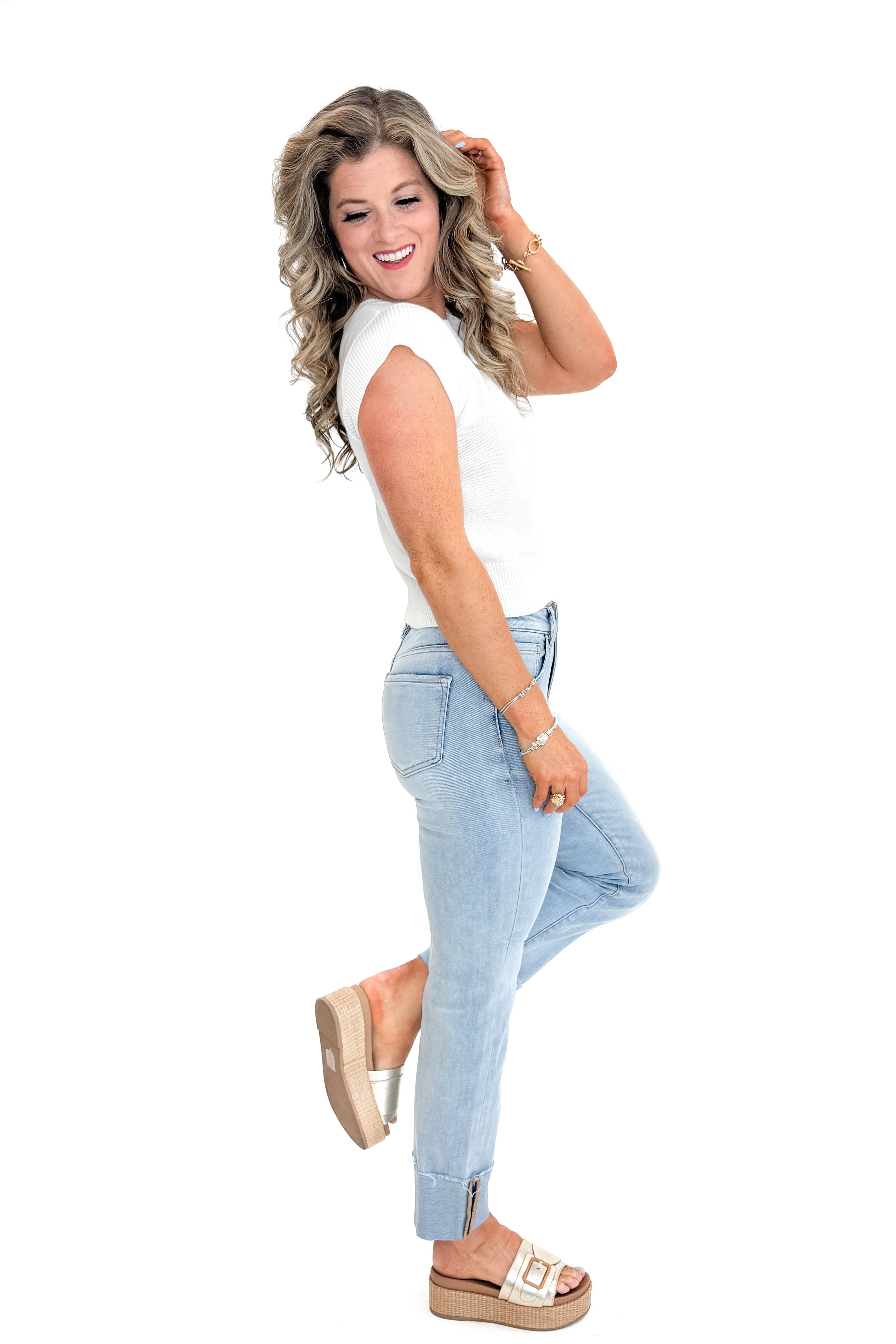 Side view of woman wearing sweater with Light Wash Relaxed Straight Jeans by Risen against white studio background.