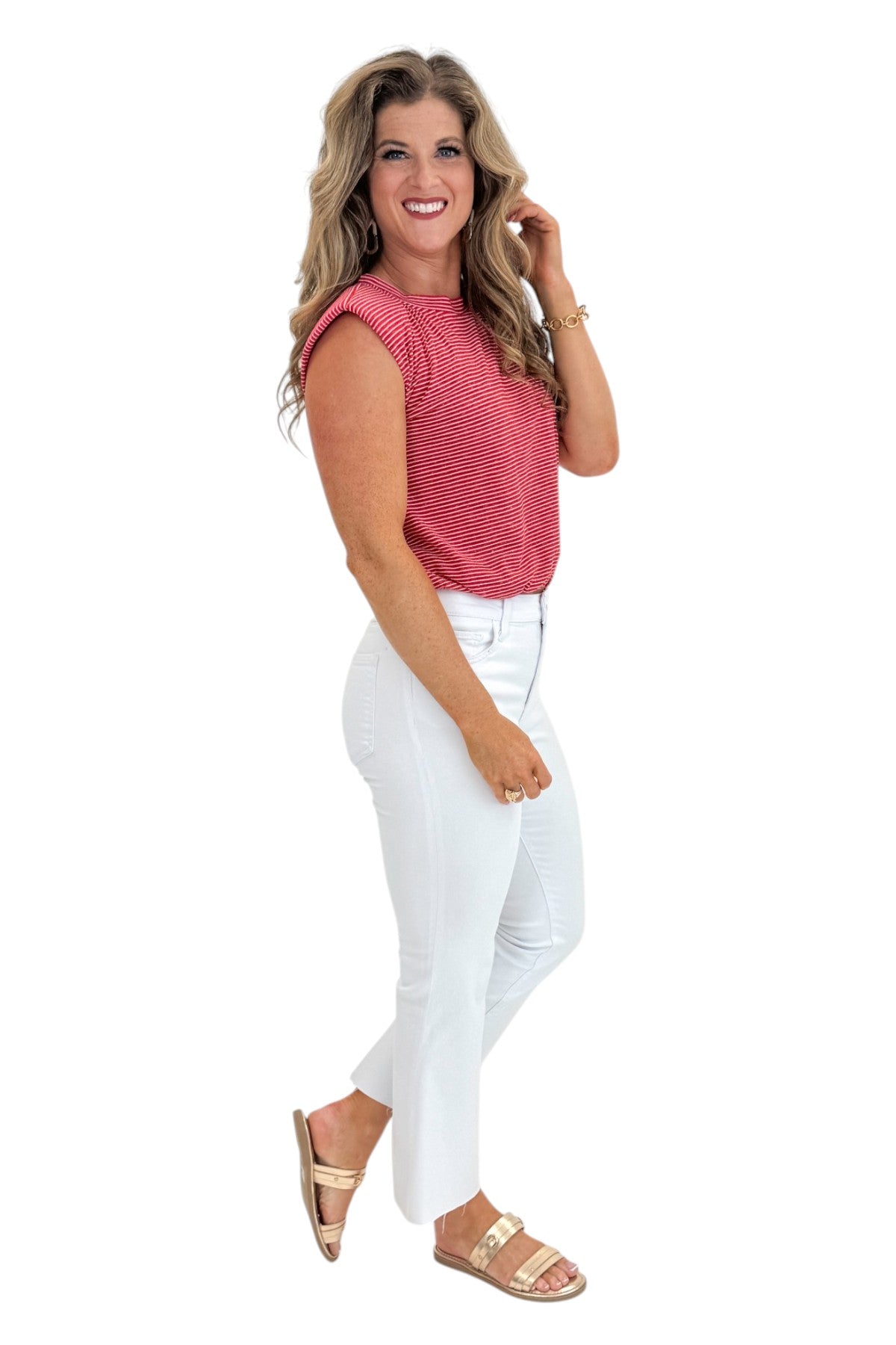 Side view of woman wearing Swagger Boutique’s Red Striped Bubble Hem Sleeveless Top with jeans against white studio background.