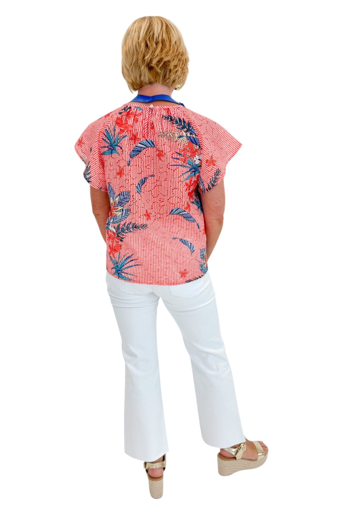 Back view of woman wearing Swagger Boutiqueβs Red Striped & Floral Short Sleeve Top with jeans against white studio background.