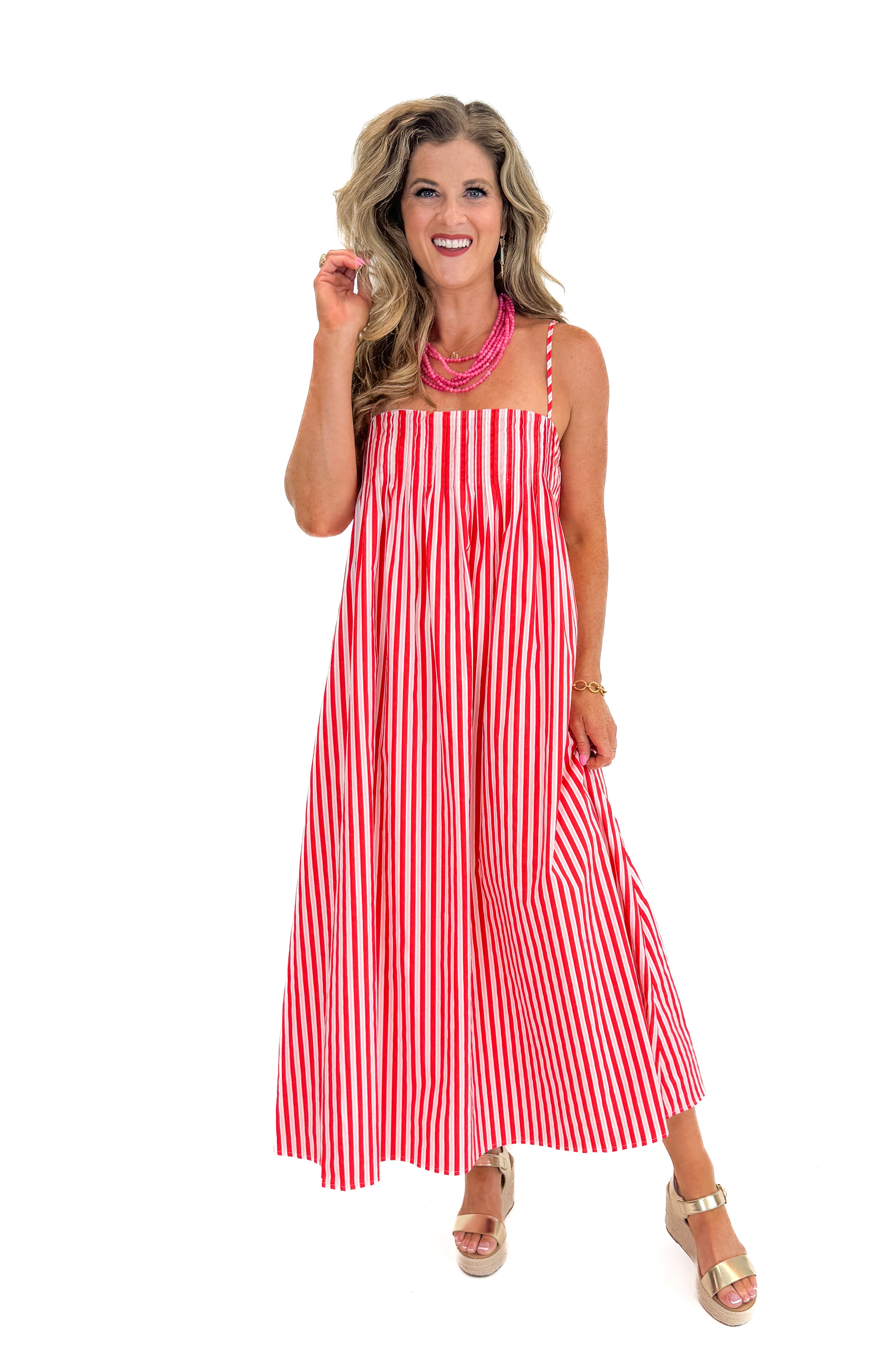 Front view of woman wearing Swagger Boutiqueβs Red & Pink Striped Maxi Dress with sandals against white studio background.
