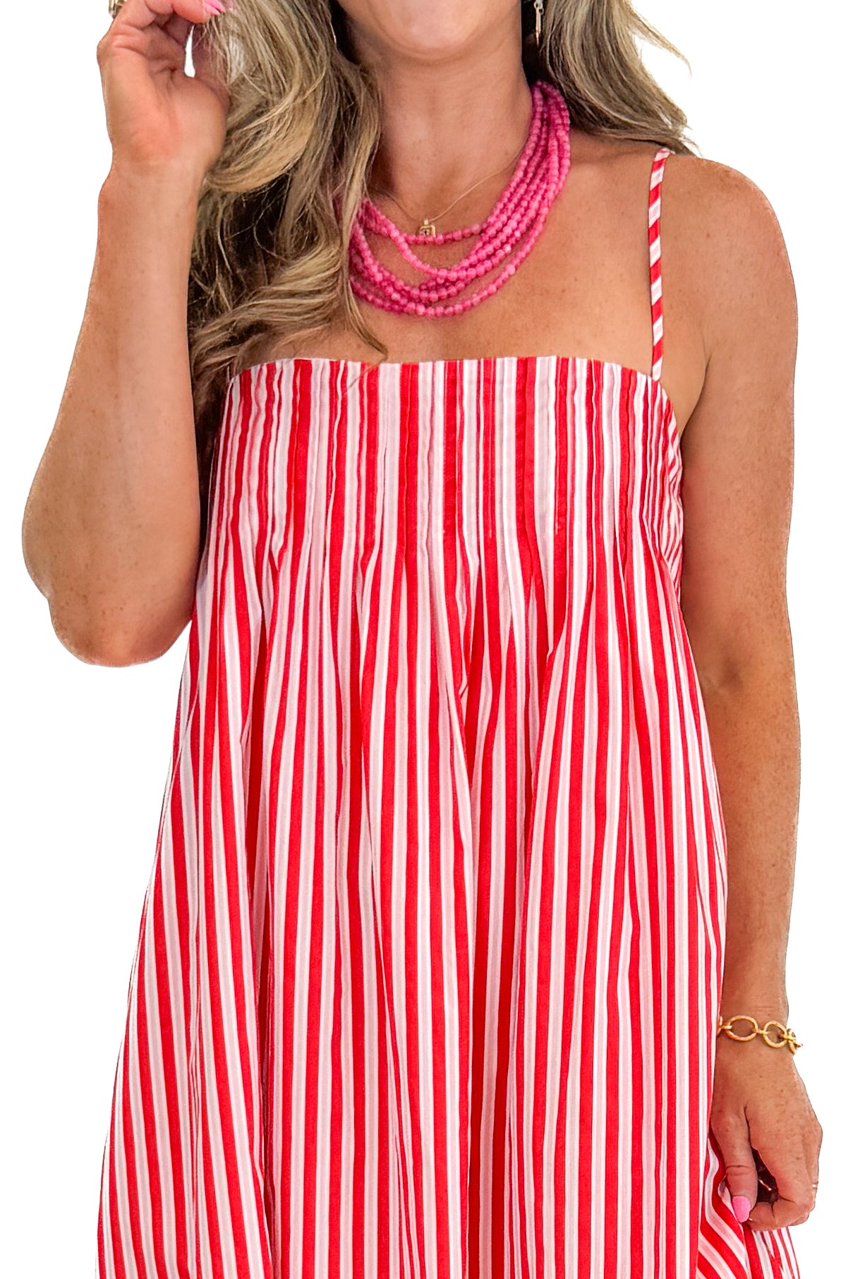 Front detail view of woman wearing Swagger Boutiqueβs Red & Pink Striped Maxi Dress with sandals against white studio background.