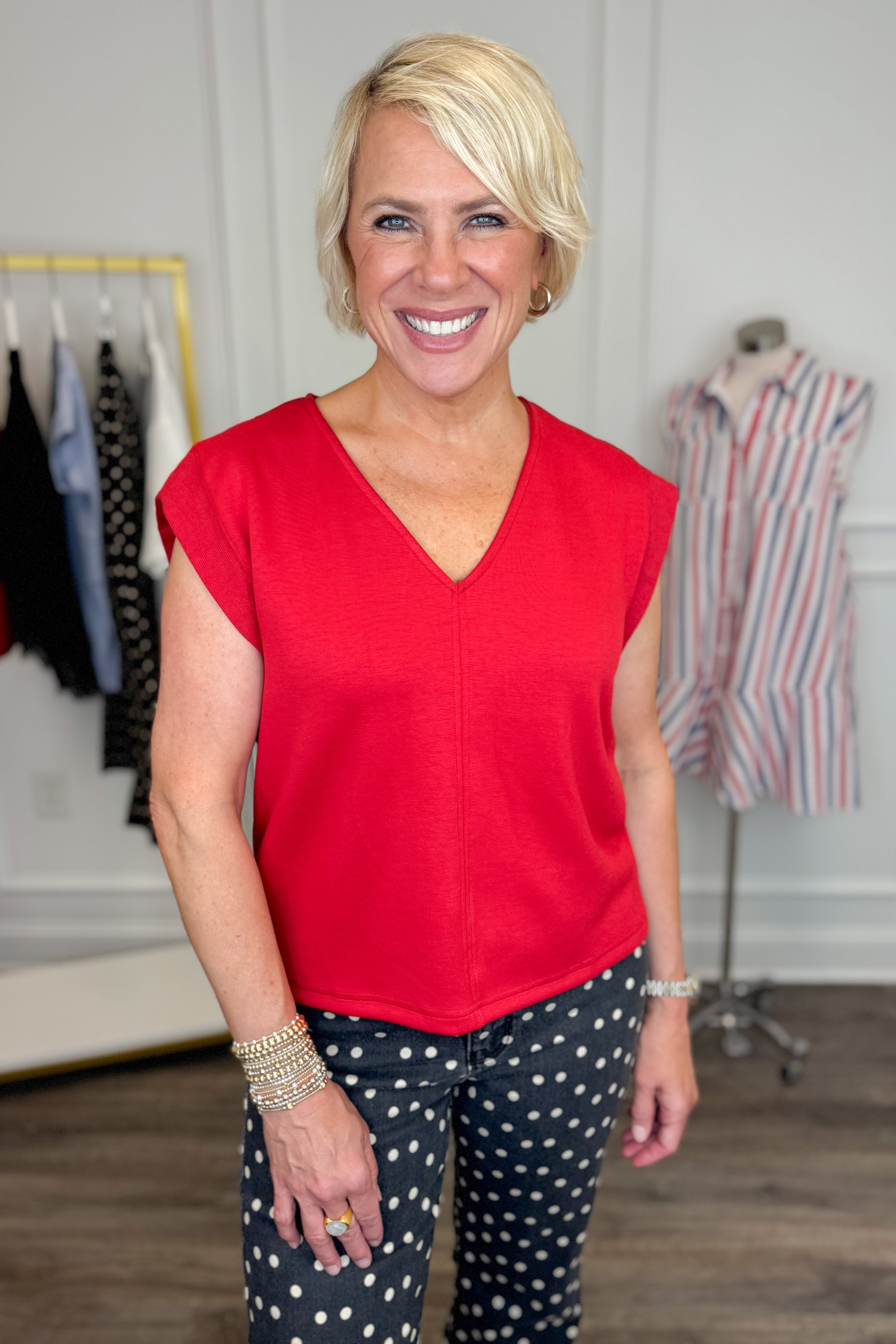 Front view of woman wearing Swagger Boutiqueβs Red V-Neck Tank by Entro with jeans against white studio background.