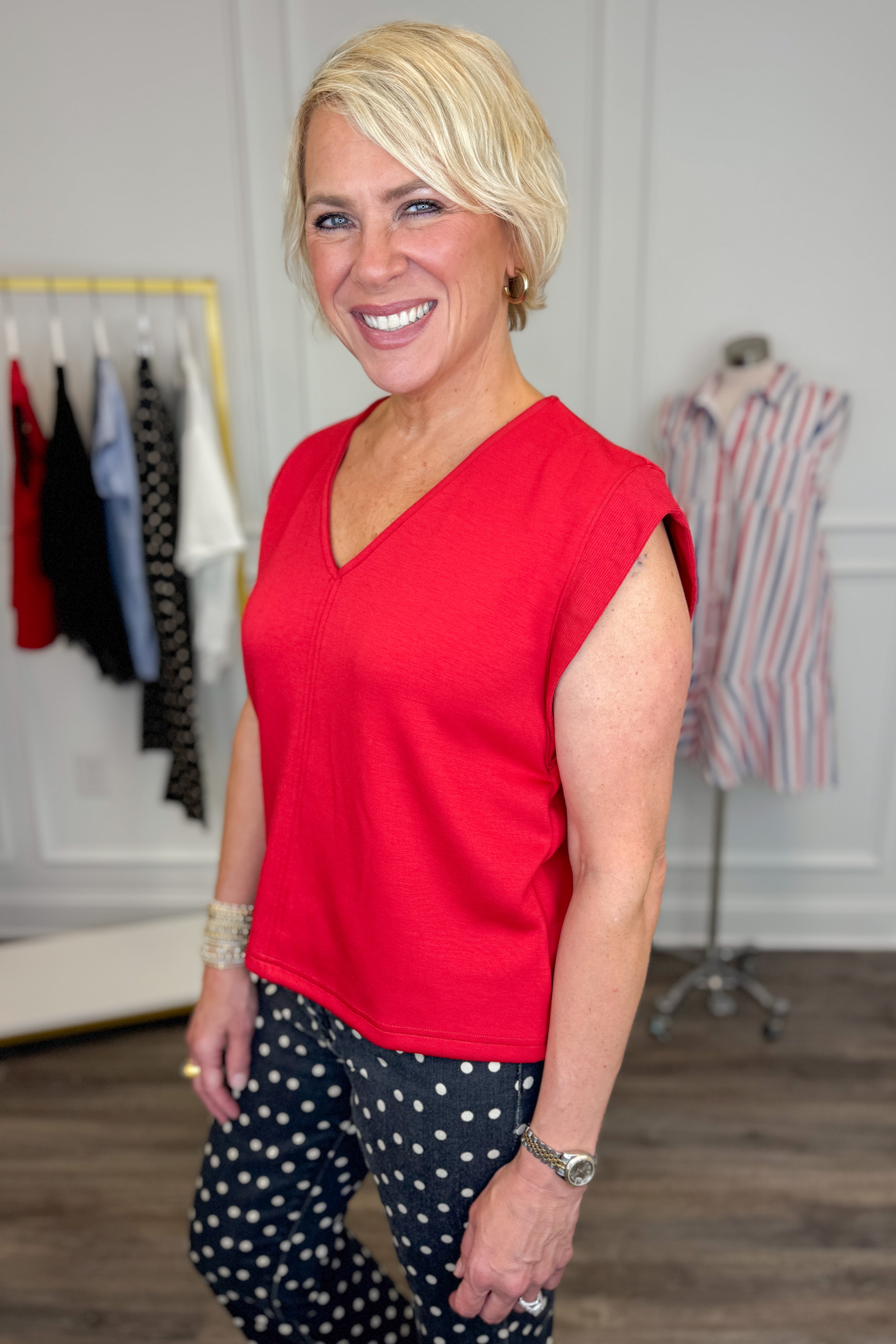 Side view of woman wearing Swagger Boutiqueβs Red V-Neck Tank by Entro with jeans against white studio background.