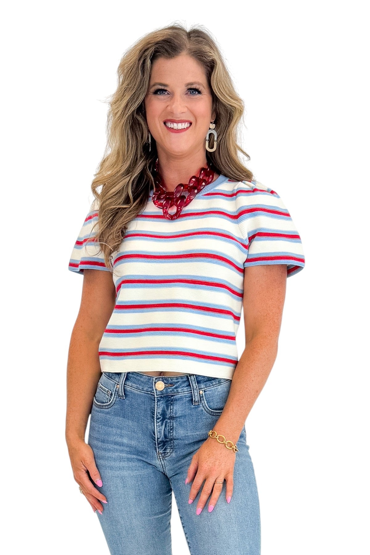 Front view of woman wearing Swagger Boutiqueβs Red, White & Blue Striped Top by Entro with jeans against white studio background.