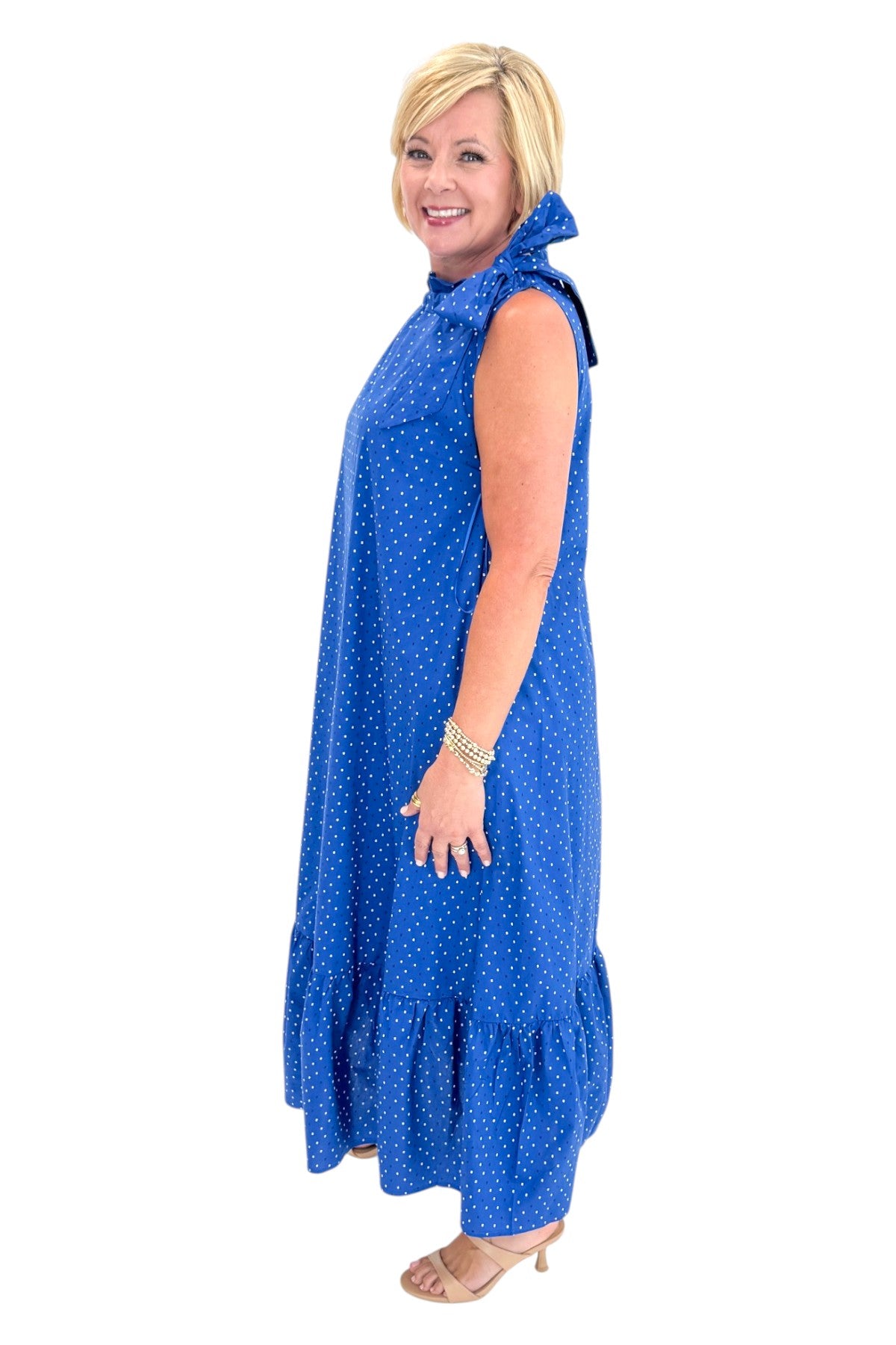 Side view of woman wearing Swagger Boutiqueās Royal Blue Polka Dot Tue Neck Midi Dress against white studio background.
