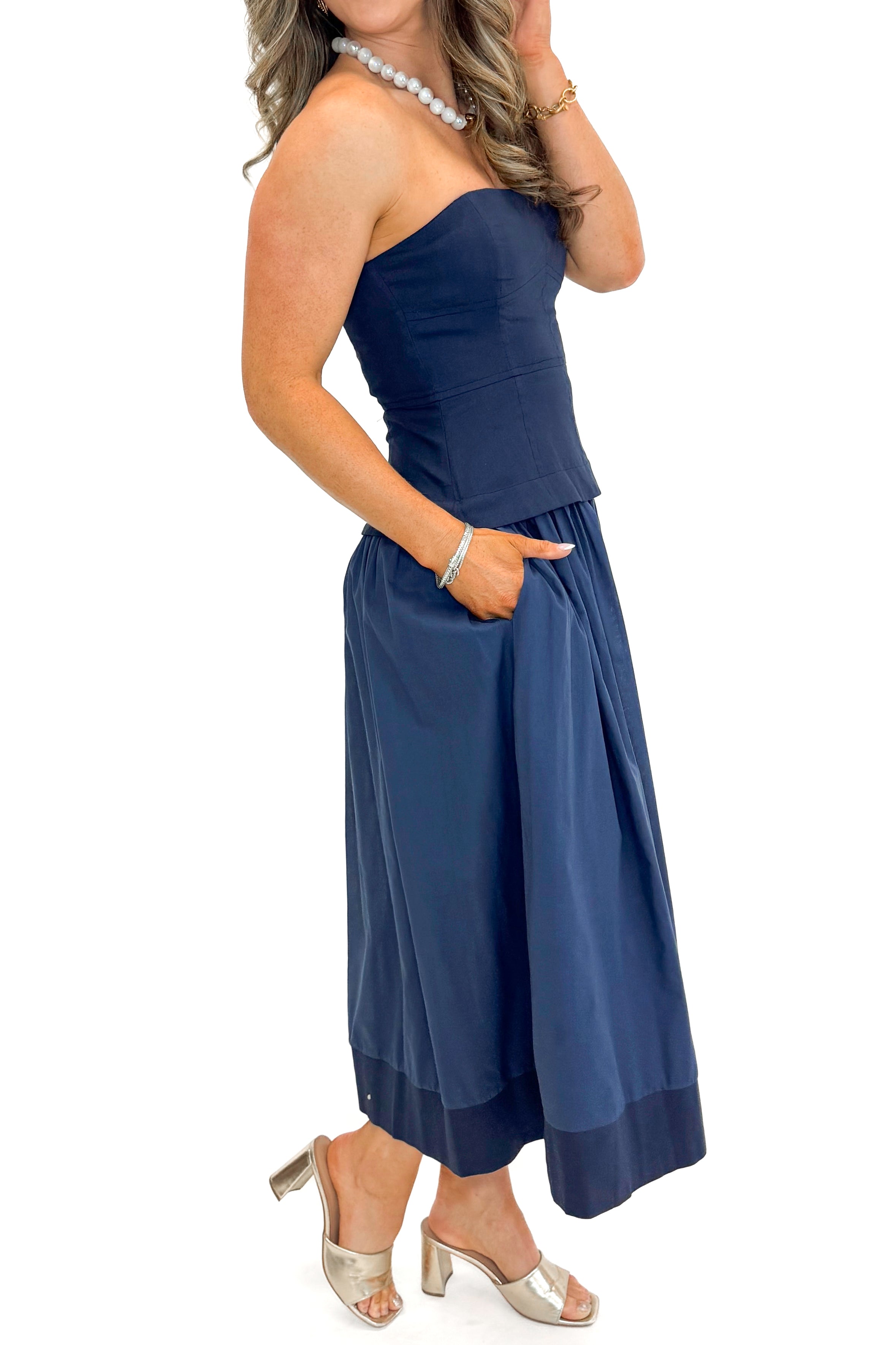 Side view of woman wearing Navy Corset Lined Midi Dress against white studio background.
