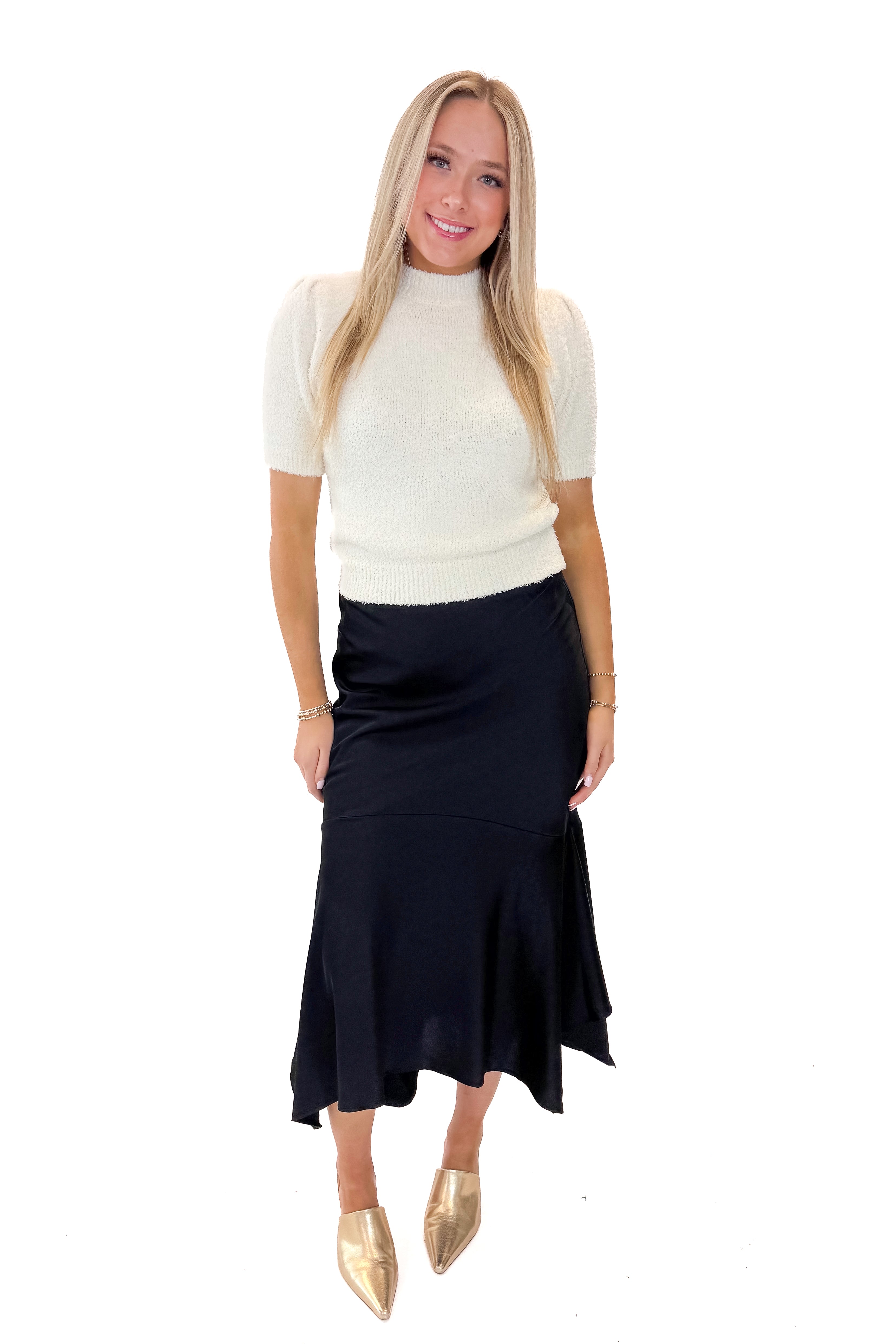 Front view of woman wearing Black Satin Handkerchief Hem Midi Skirt with sweater against white studio background.