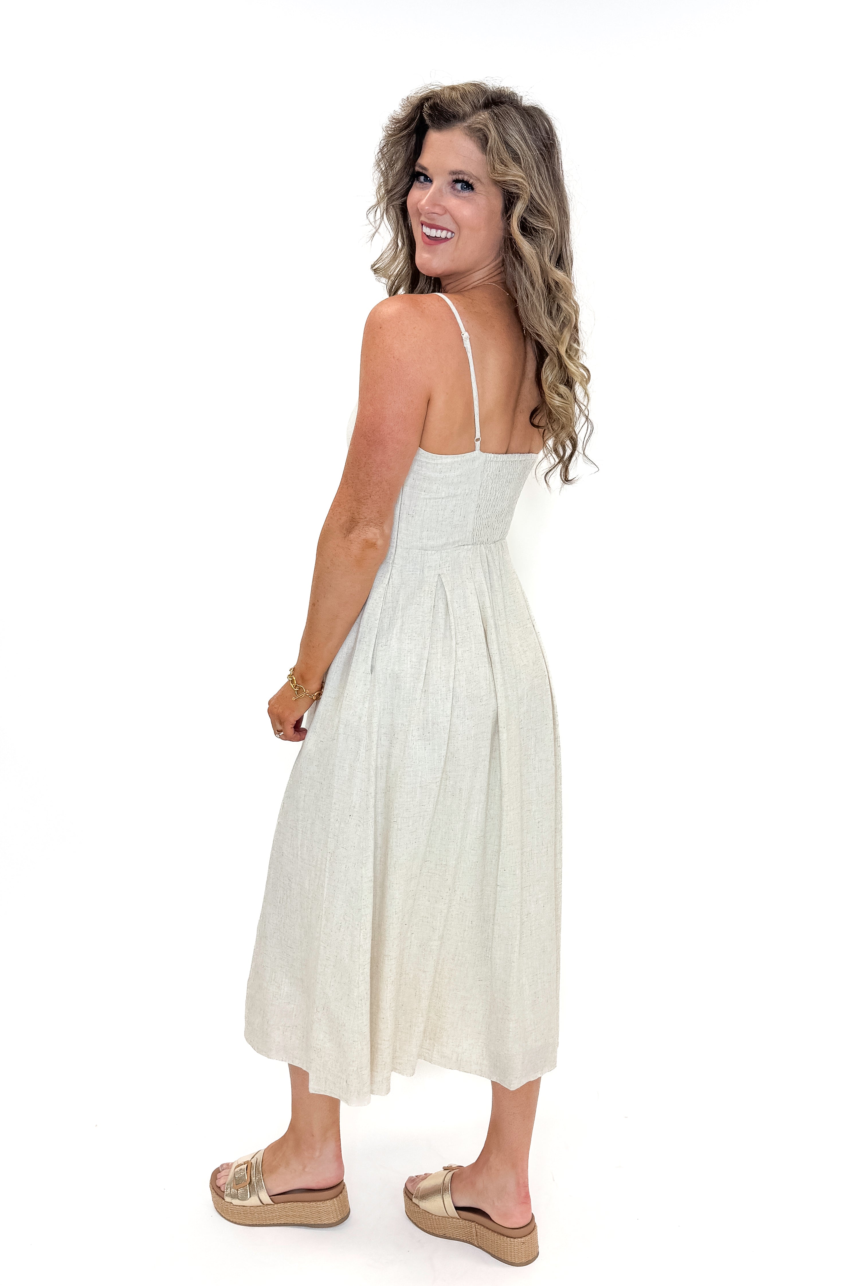 Side view of woman wearing Linen Pleat Detail Tank Dress with sandals against white studio background.