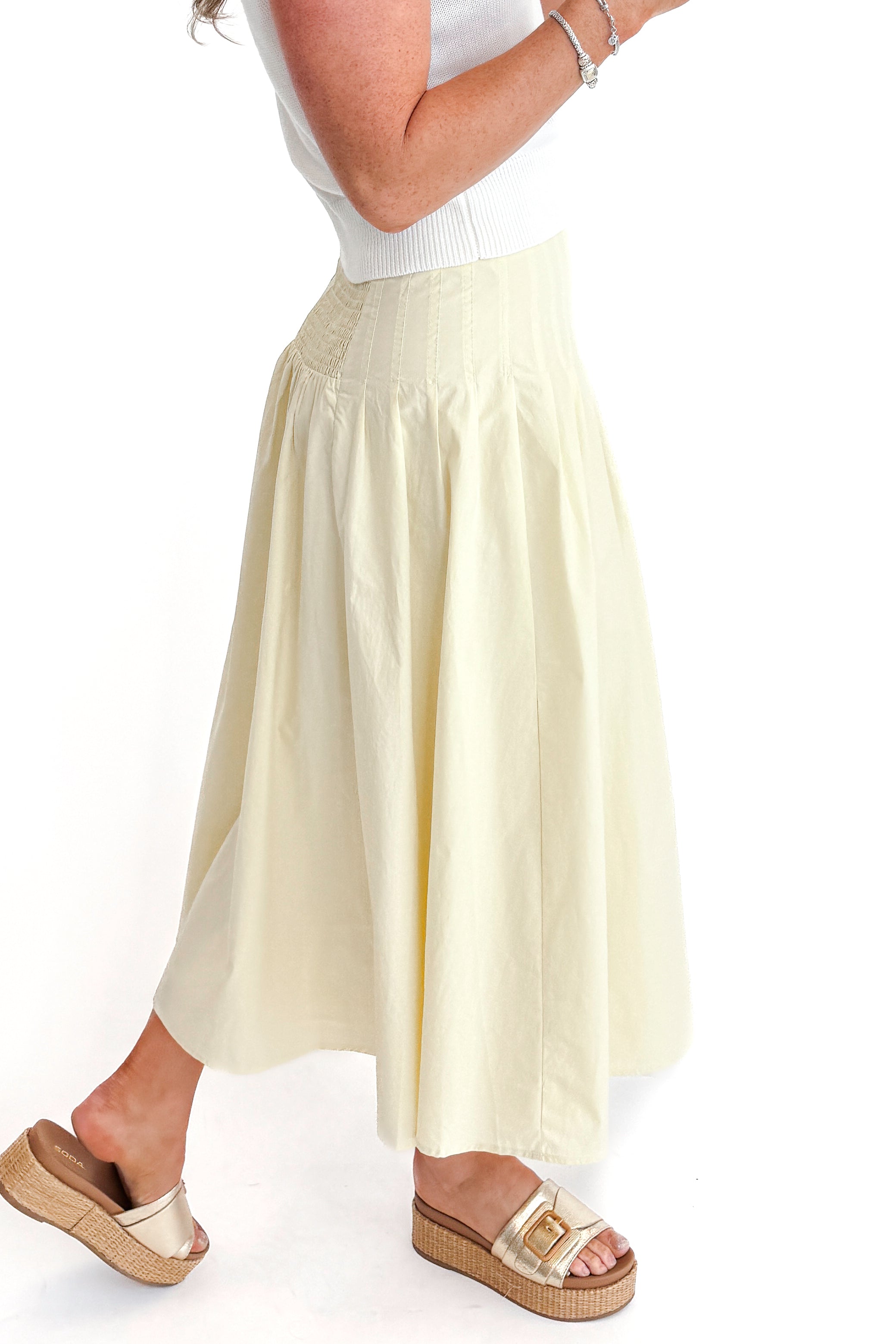 Side view of woman wearing top with Yellow Pleat Detail Midi Skirt against white studio background.