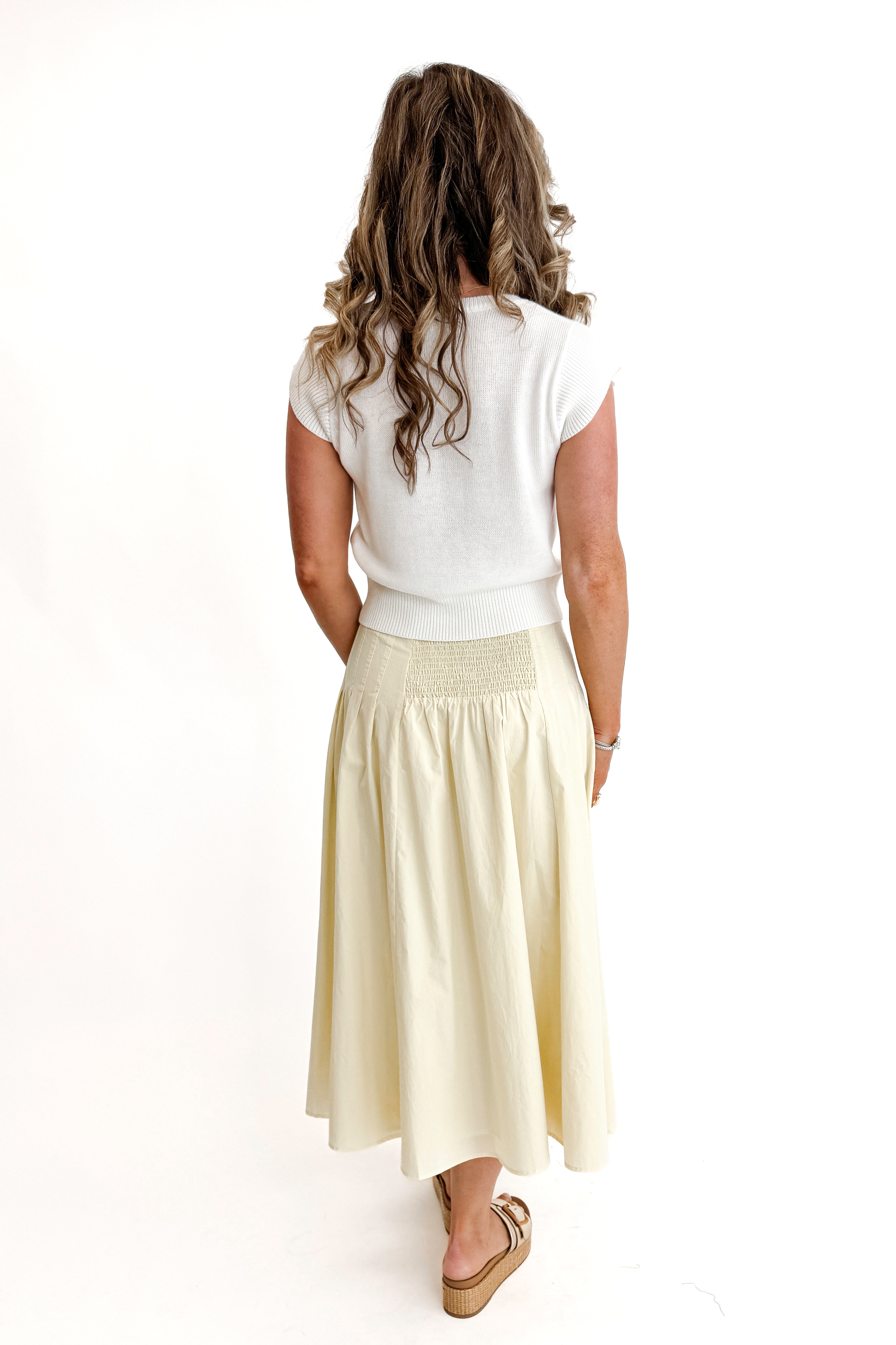 Back view of woman wearing top with Yellow Pleat Detail Midi Skirt against white studio background.