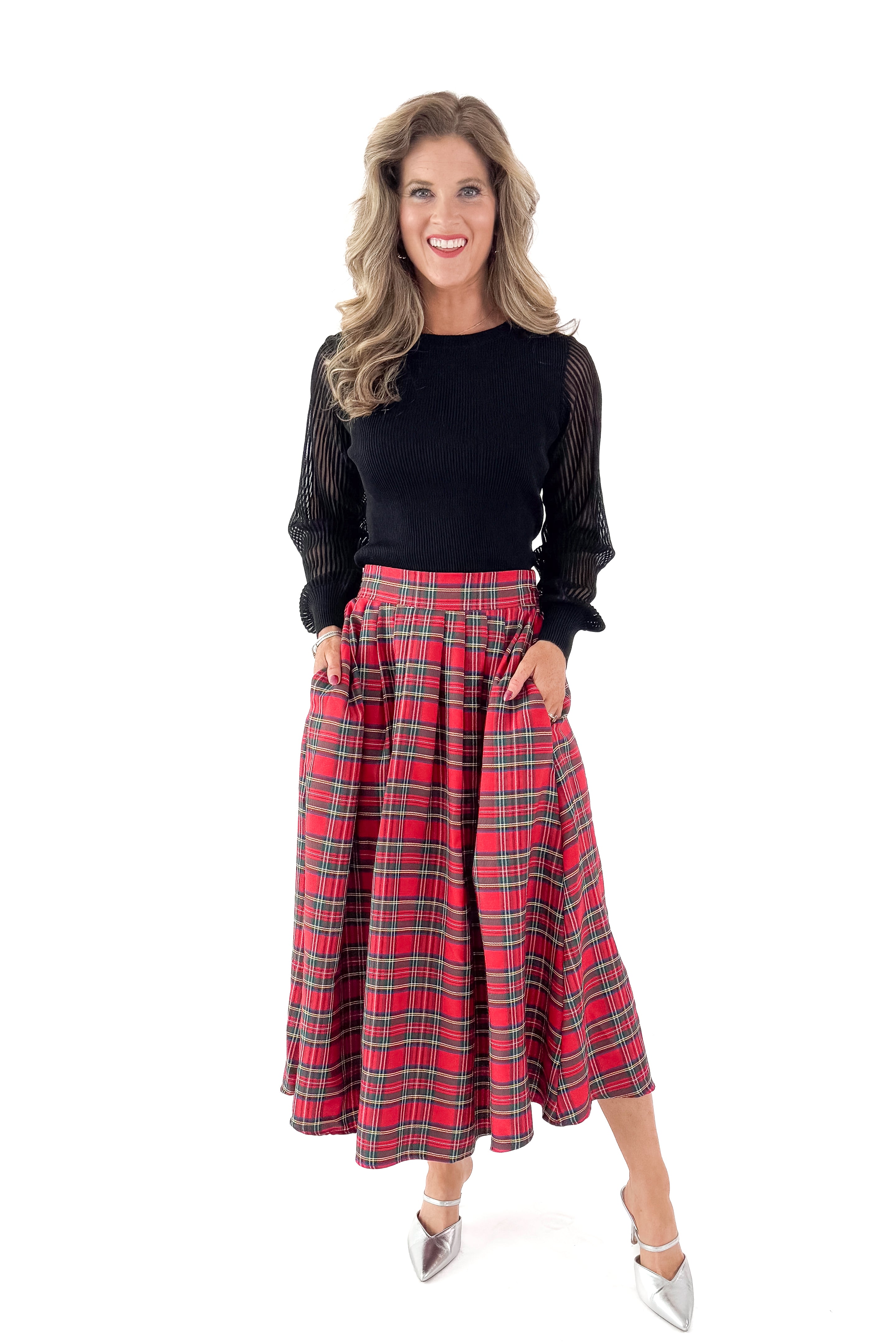 Front view of woman wearing white top with red tartan skirt against white studio background.
