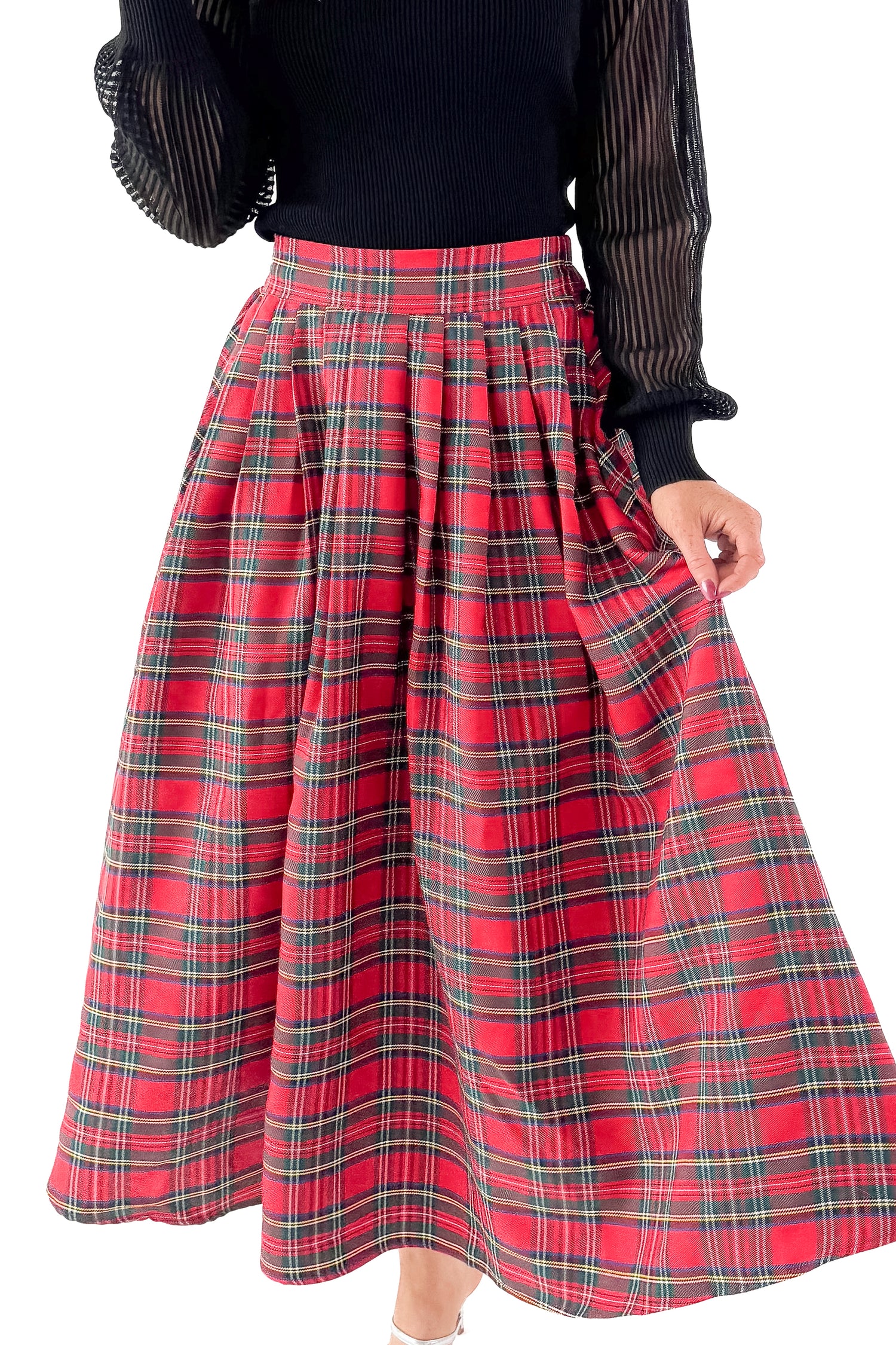 Front detailed view of woman wearing black top with red tartan skirt against white studio background.