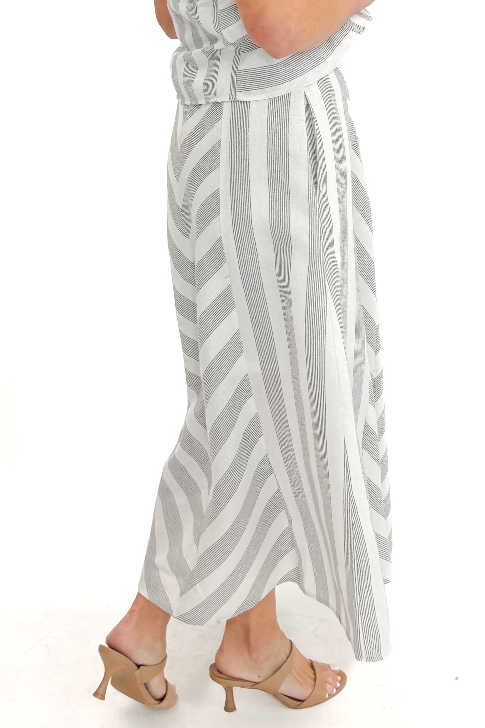 Side view of woman wearing Cream & Grey Striped Skirt by Entro with matching tank against white studio background.