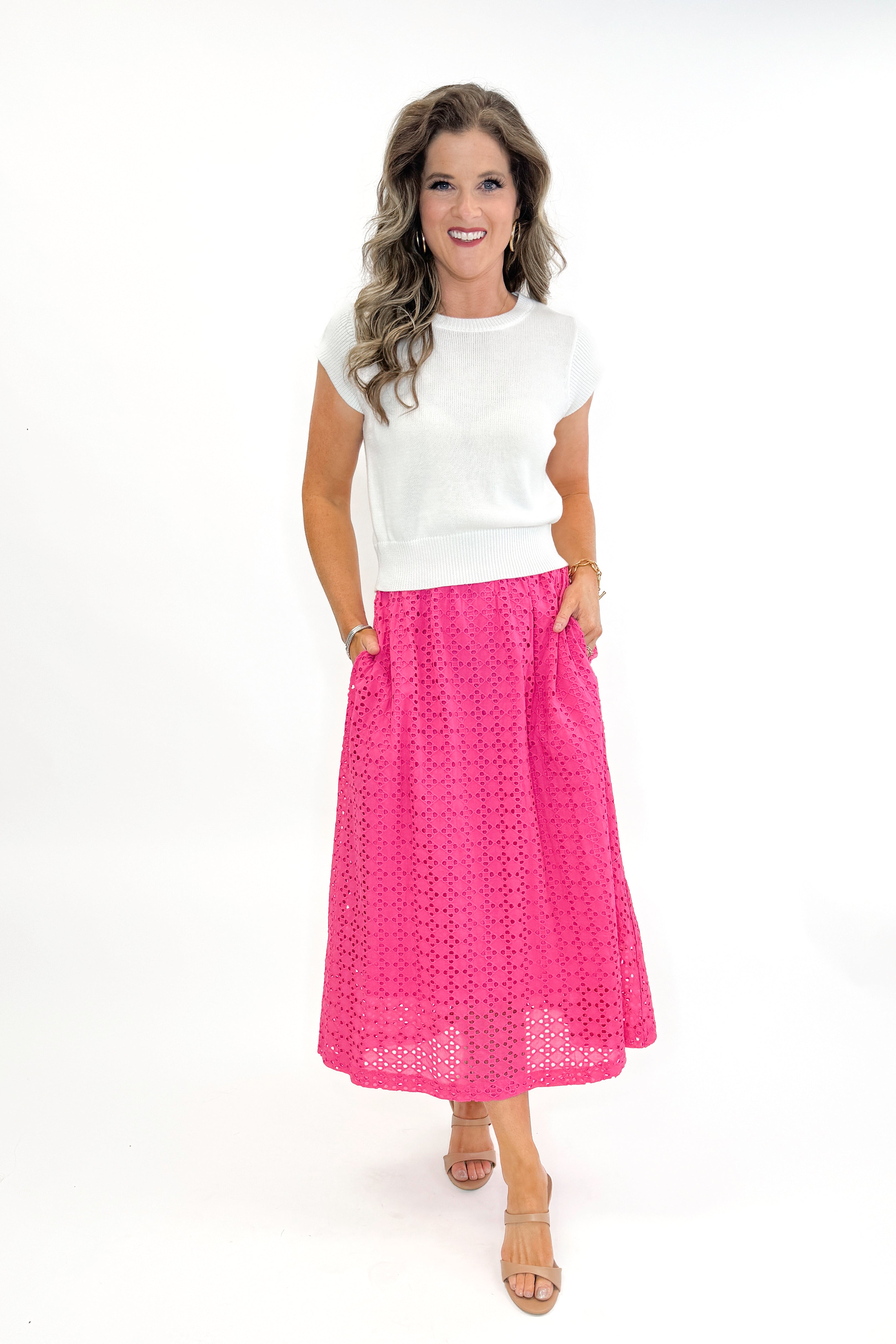 Front view of woman wearing white sweater with Hot Pink Eyelet Midi Skirt by Entro against white studio background.
