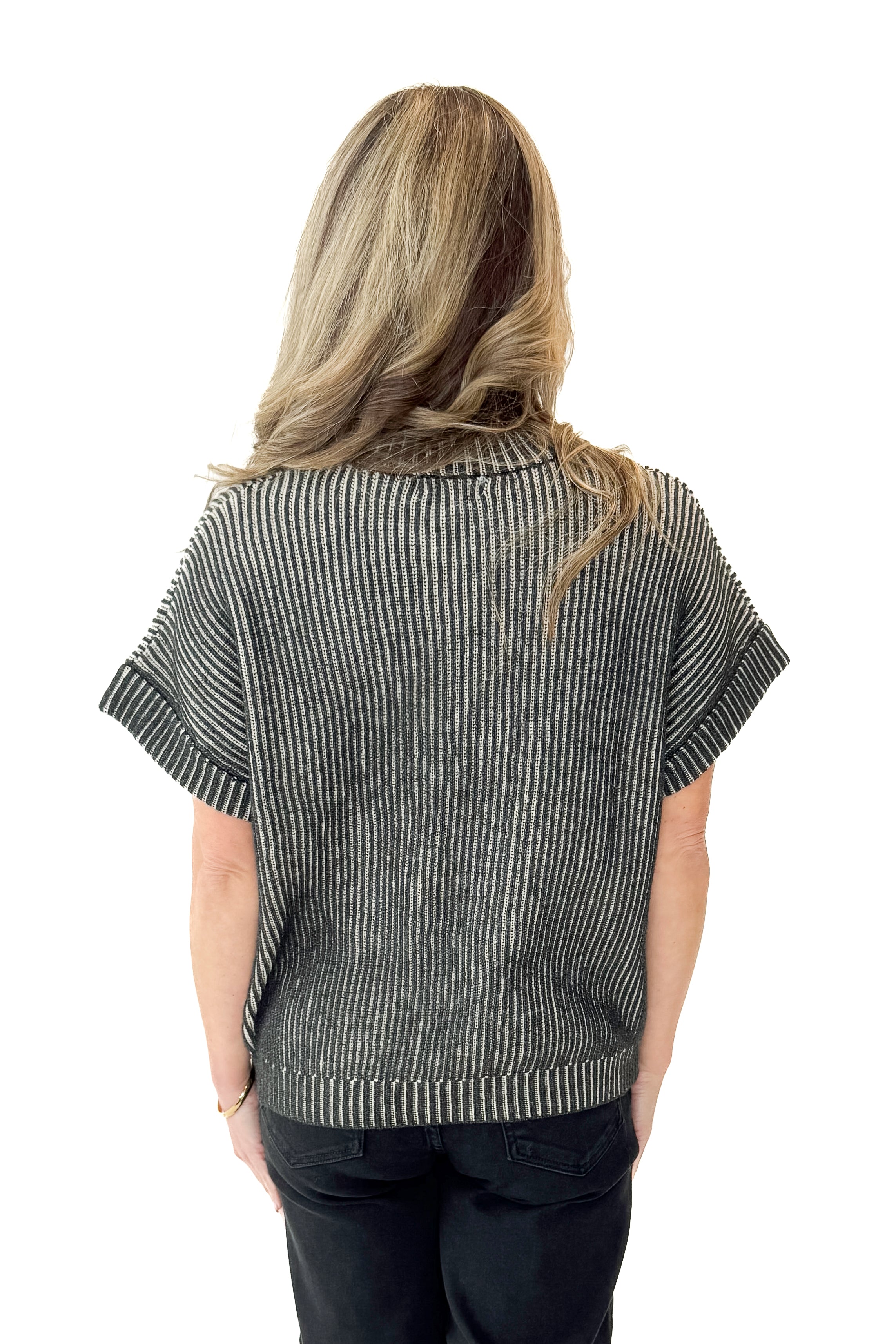 Back view of woman wearing Black & White Ribbed Short Sleeve Sweater with jeans against white studio background.