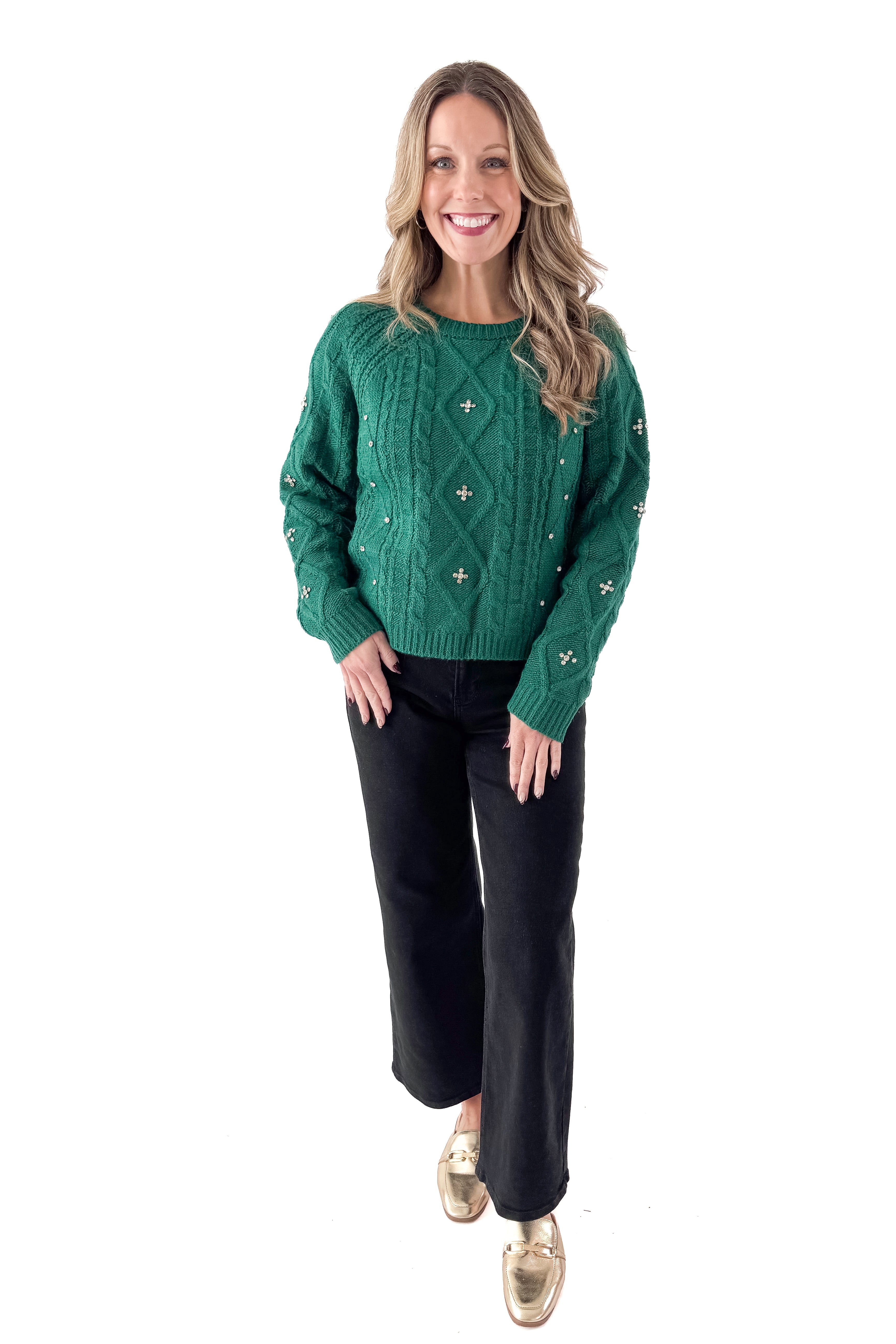 Front view of woman wearing Green Cable Knit Sweater With Rhinestones with jeans against white studio background.