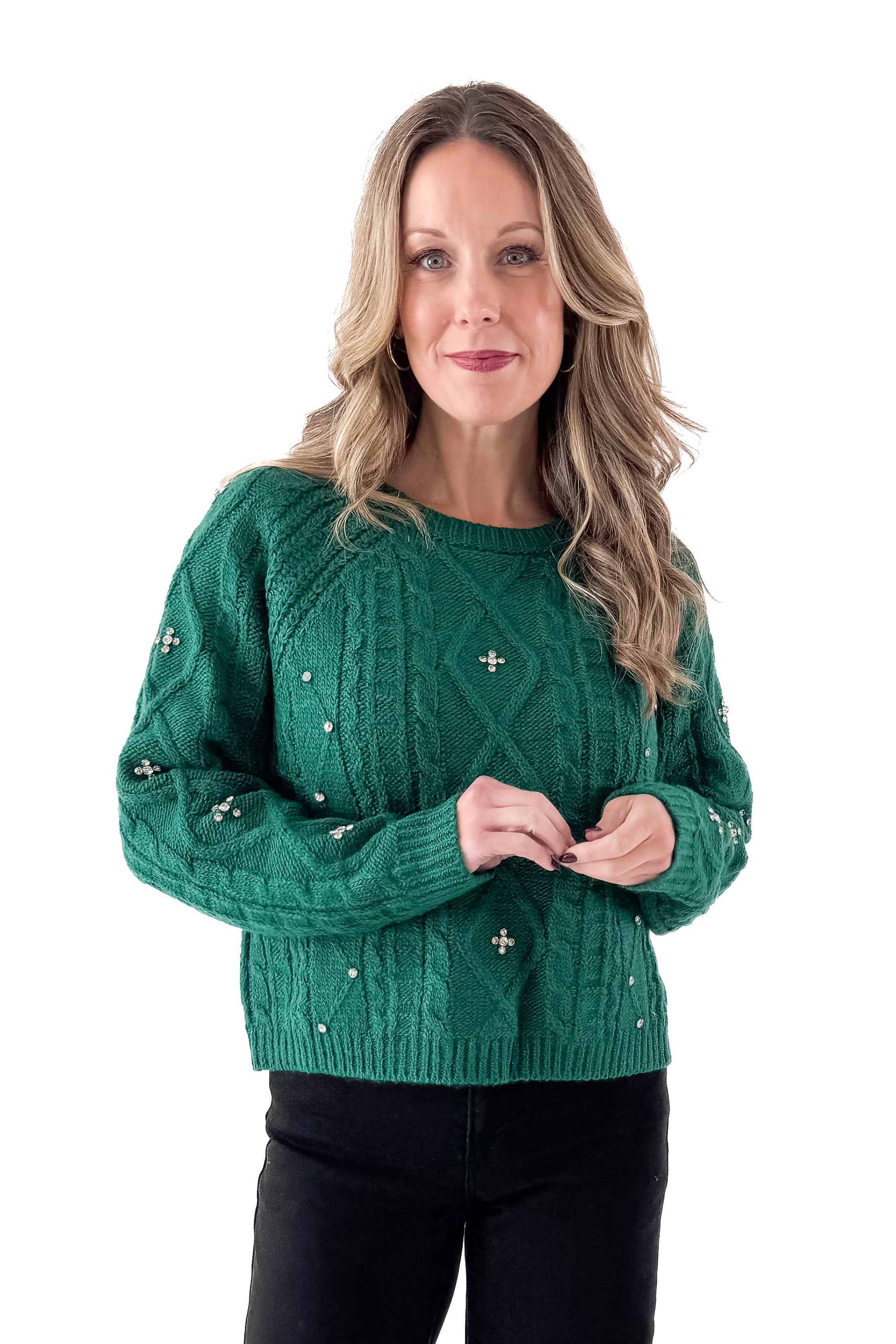 Front view of woman wearing Green Cable Knit Sweater With Rhinestones with jeans against white studio background.