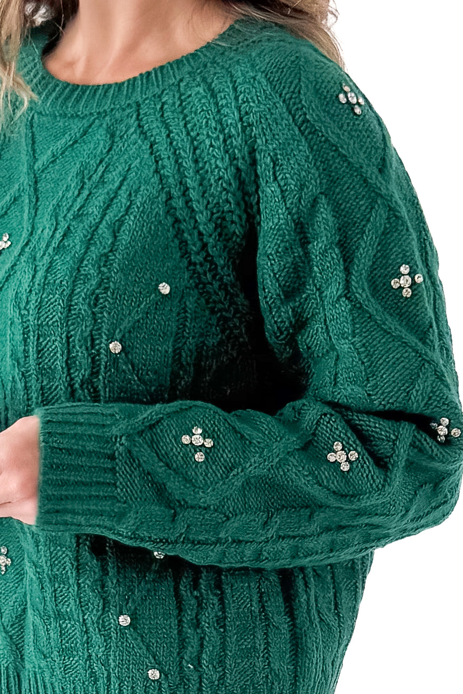 Detailed view of woman wearing Green Cable Knit Sweater With Rhinestones with jeans against white studio background.