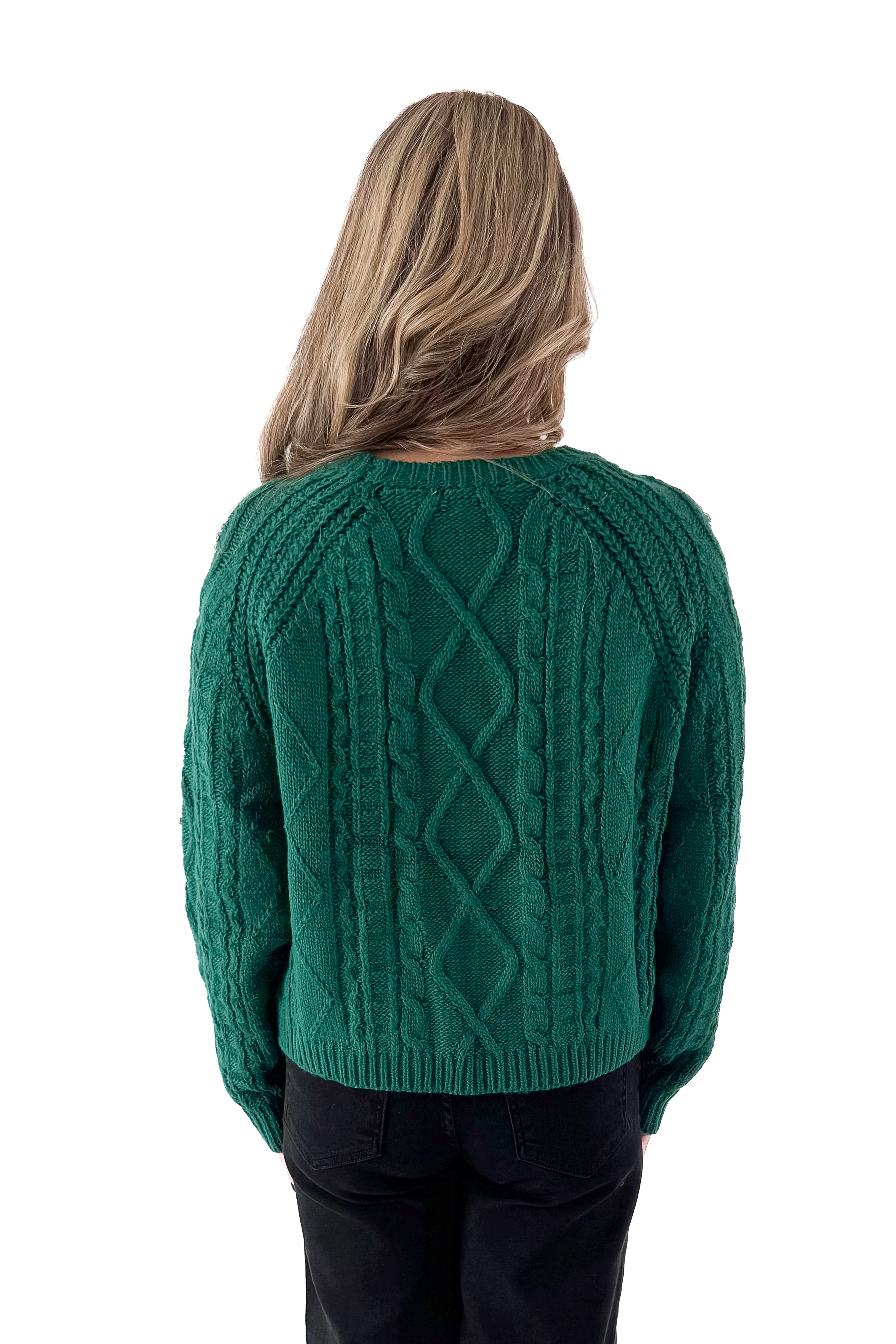 Back view of woman wearing Green Cable Knit Sweater With Rhinestones with jeans against white studio background.