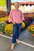 Woman outside wearing Washed Mauve Puff Sleeve Sweatshirt by She + Sky and jeans with mums in the background.