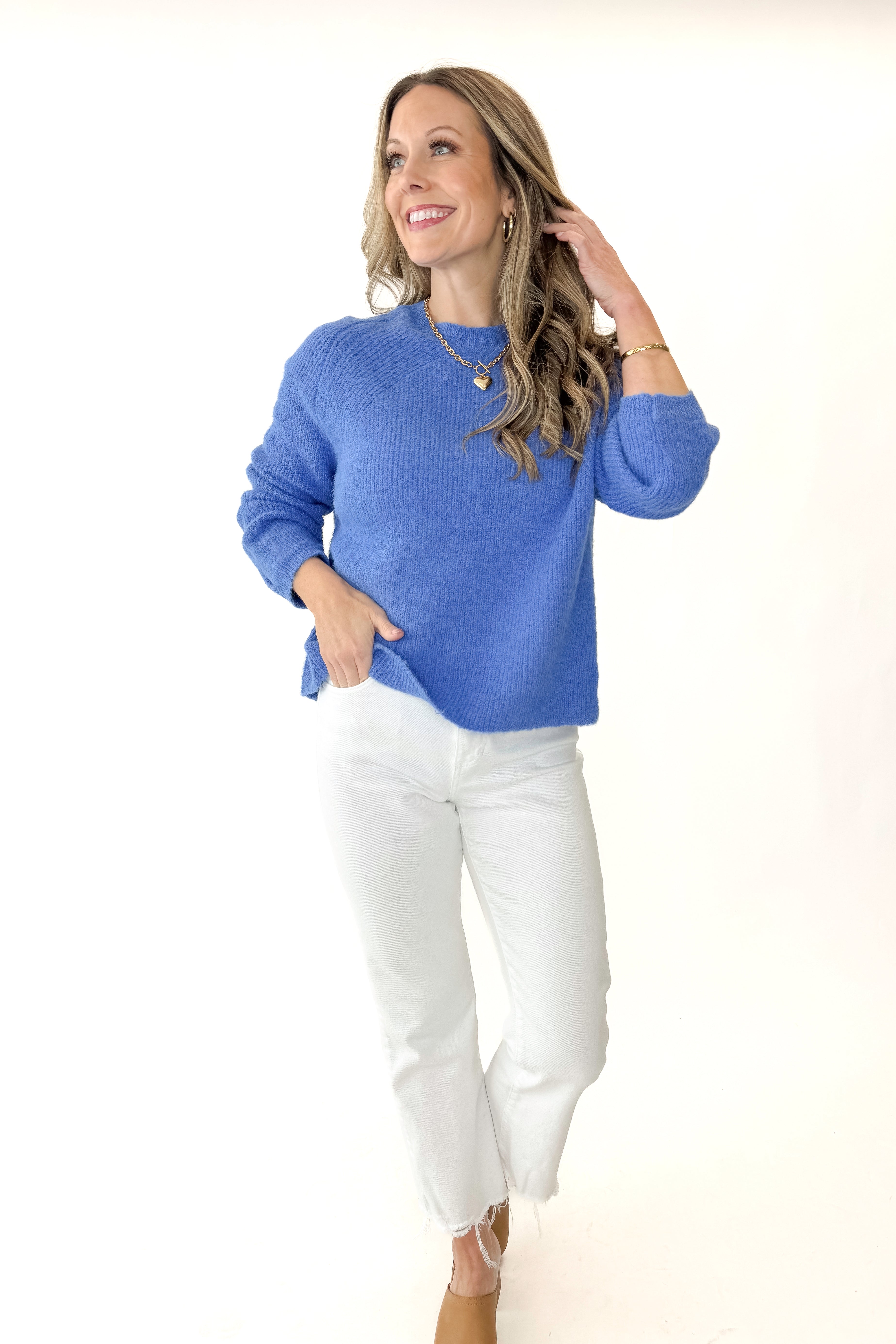 Front view of woman wearing Blue Ribbed Sweater with jeans against white studio background.