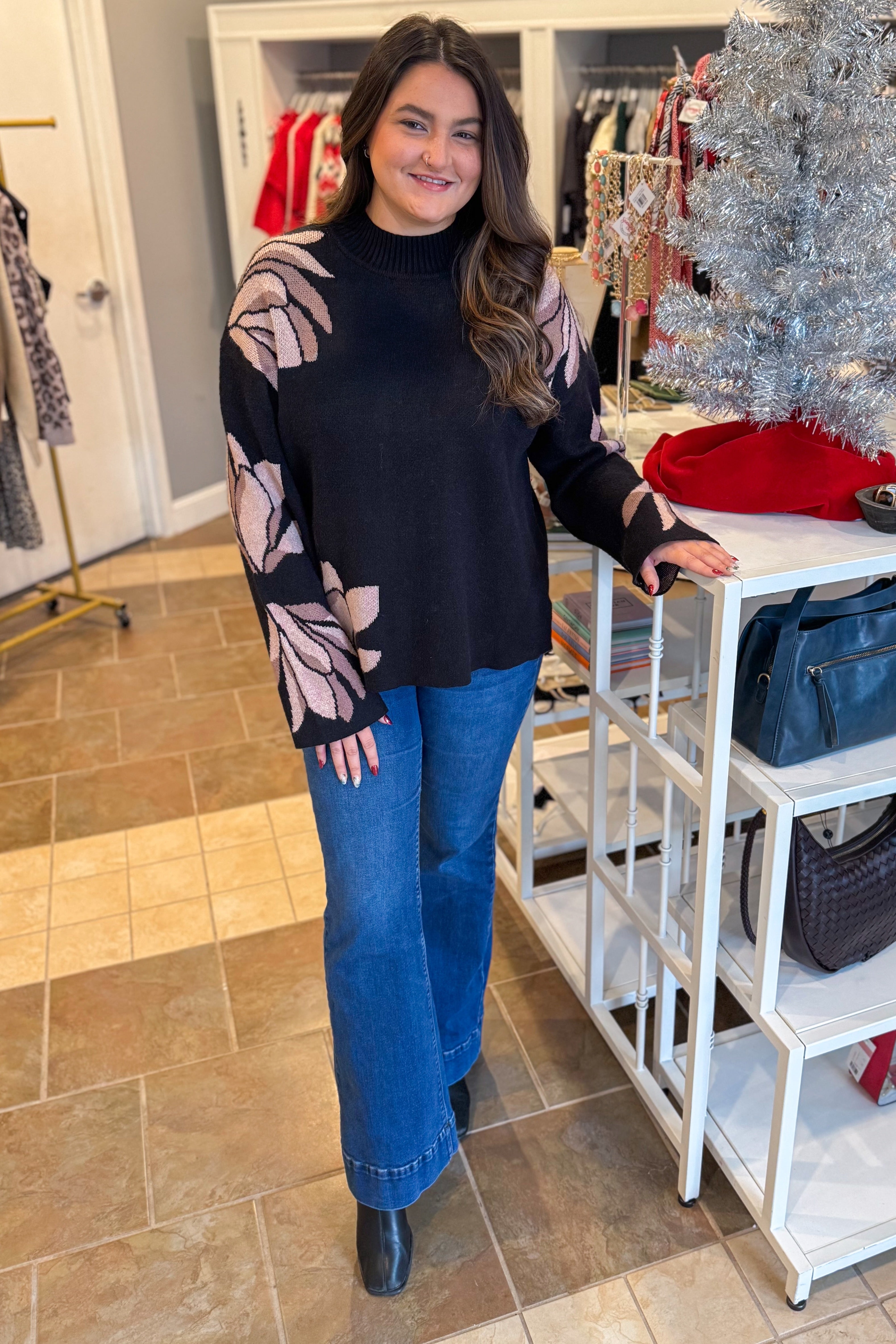 Front view of woman wearing Black With Mauve Floral Print Sweater with jeans at a boutique.