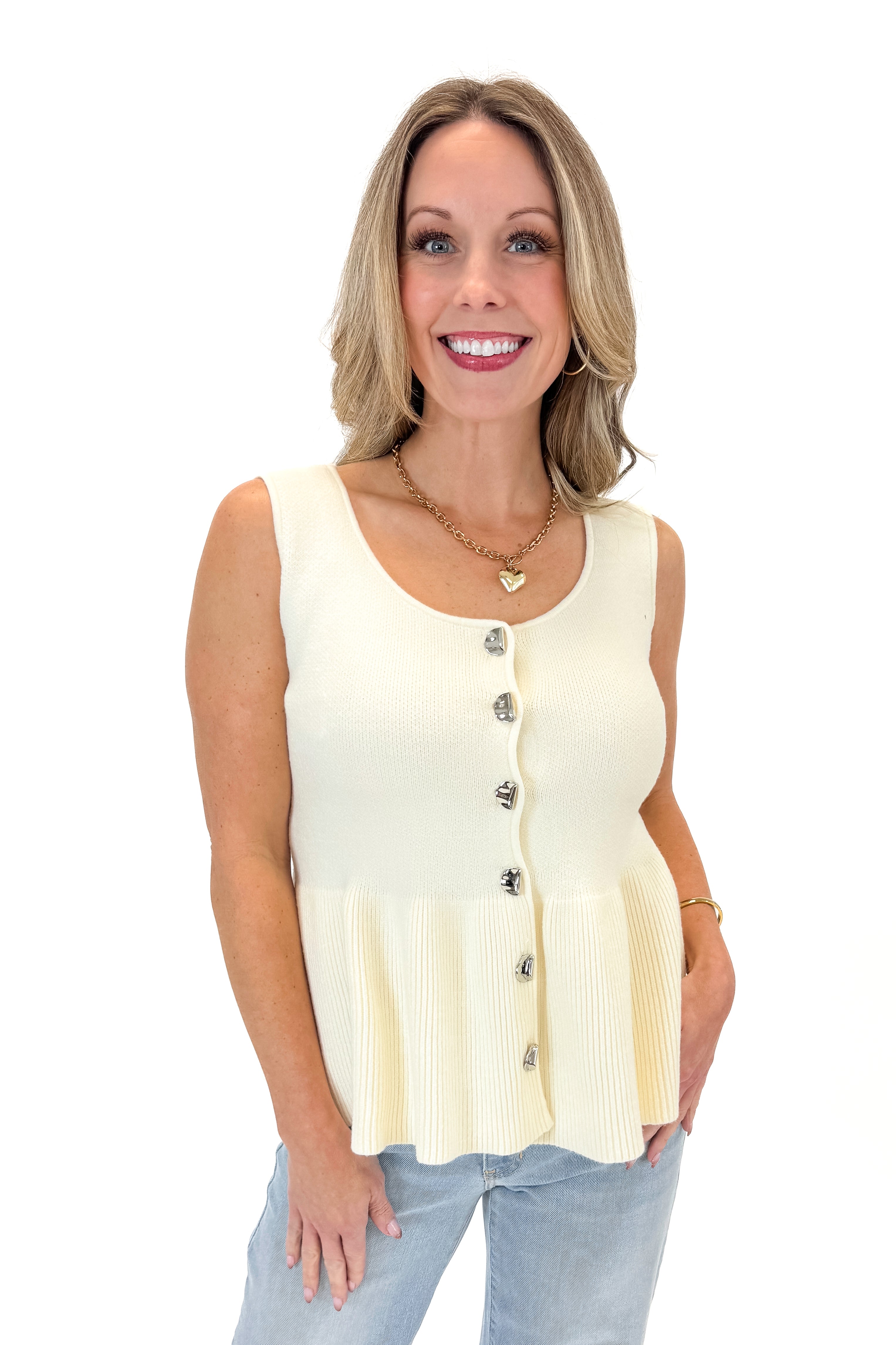 Front view of woman wearing Cream Peplum Sweater Tank with jeans against white studio background.