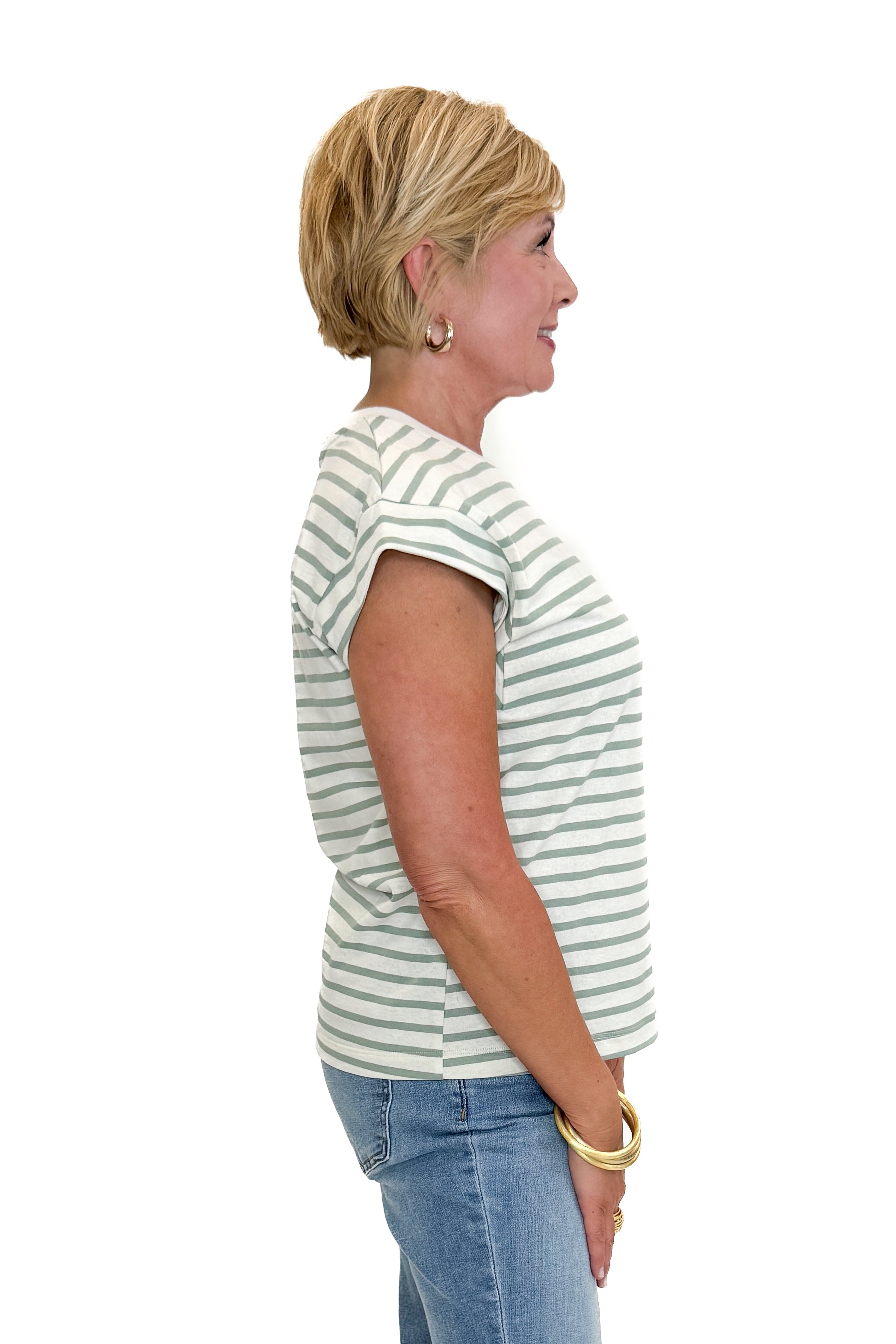 Side view of woman wearing Swagger Boutique’s Sage & Cream Stripe Cap Sleeve Tee with jeans against white studio background.