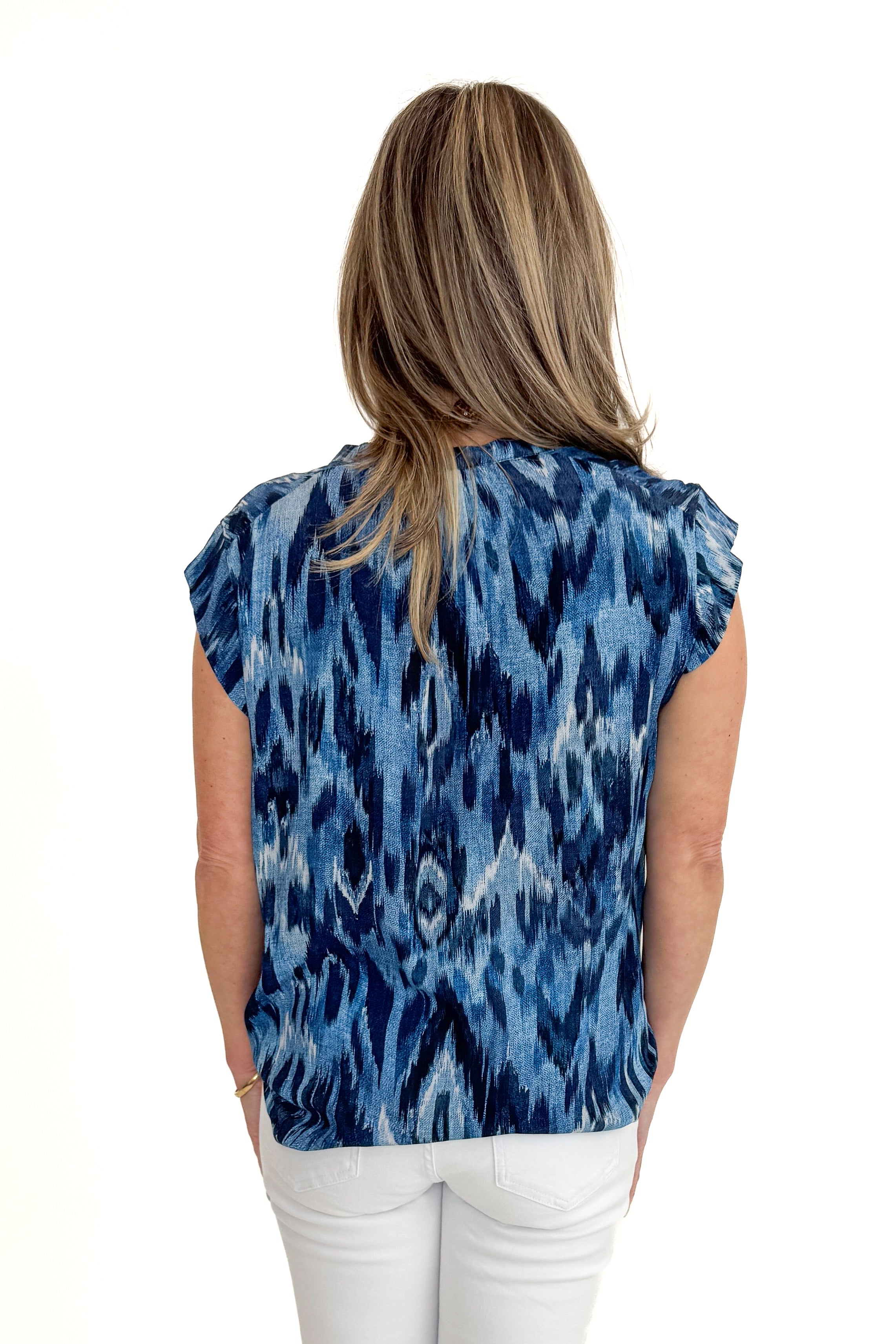 Back view of woman wearing Navy & Blue Printed V-Neck Top with jeans against white studio background.