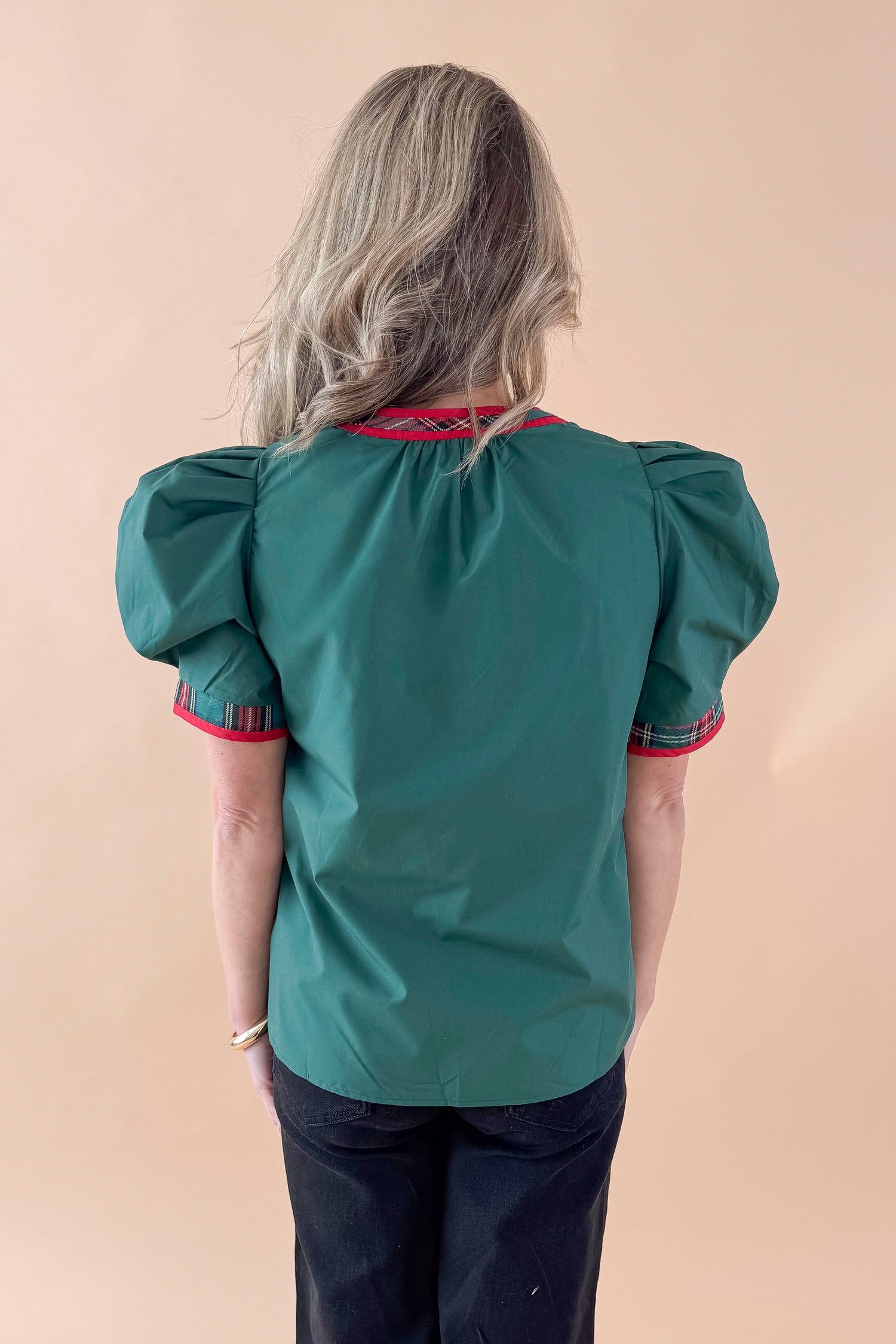 Back view of woman wearing Green With Tartan Lining Puff Sleeve Top with jeans against tan studio background.