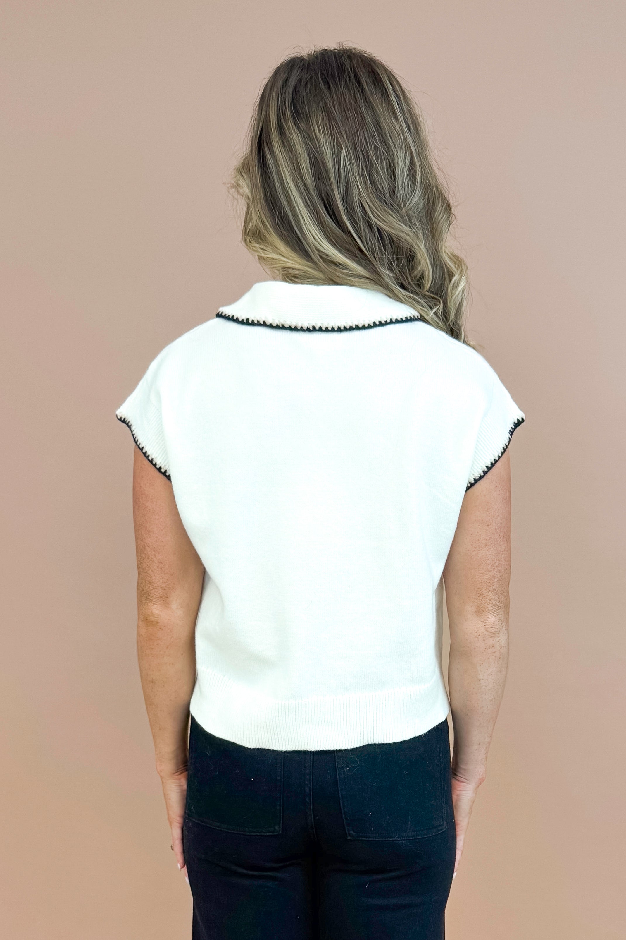 Back view picture of woman wearing Cream With Black Stitching Short Sleeve Sweater by Entro and jeans with taupe background.