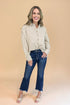 Woman wearing a striped shirt and jeans against a beige background
