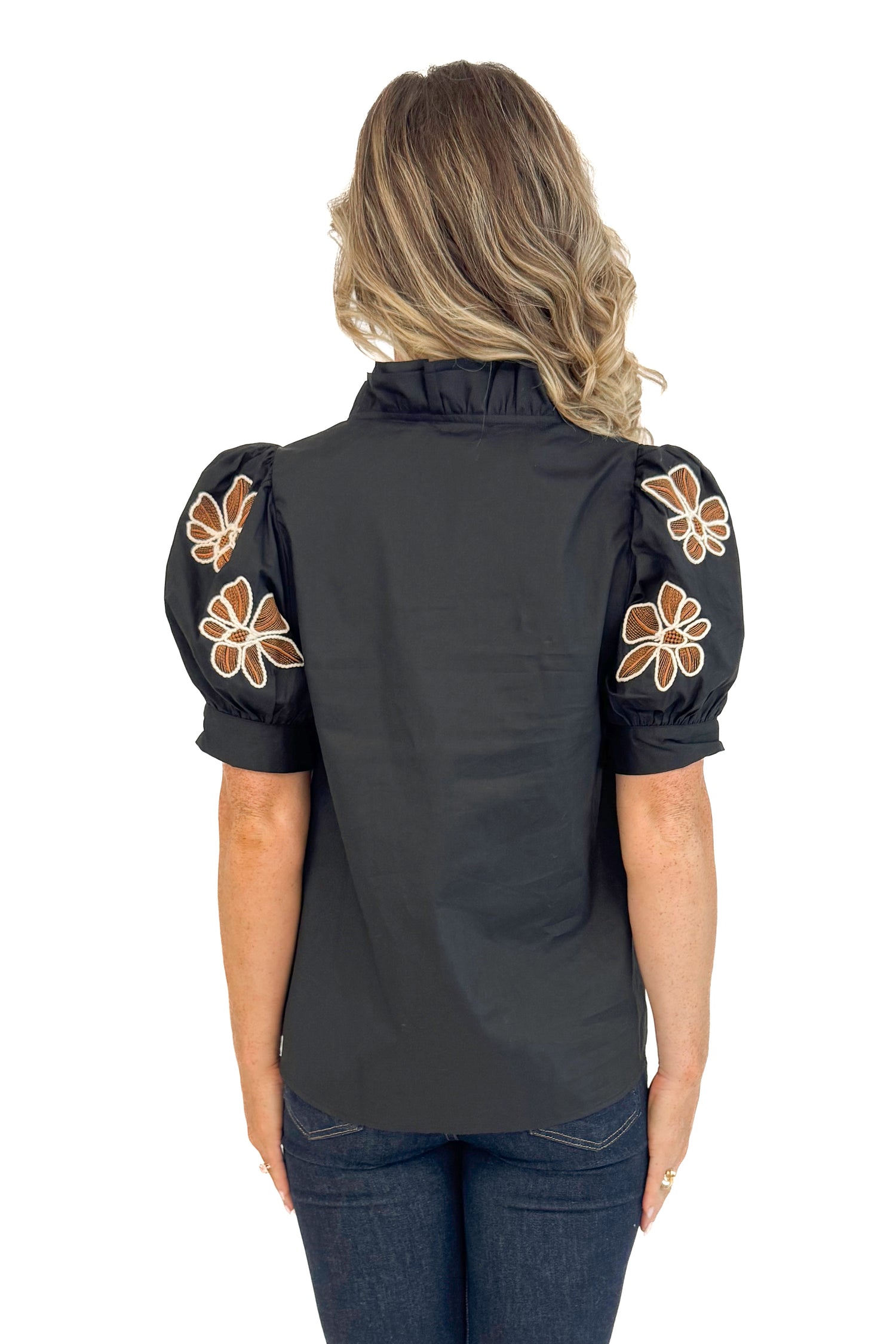 Back view of black short sleeve top showing floral embroidered design.