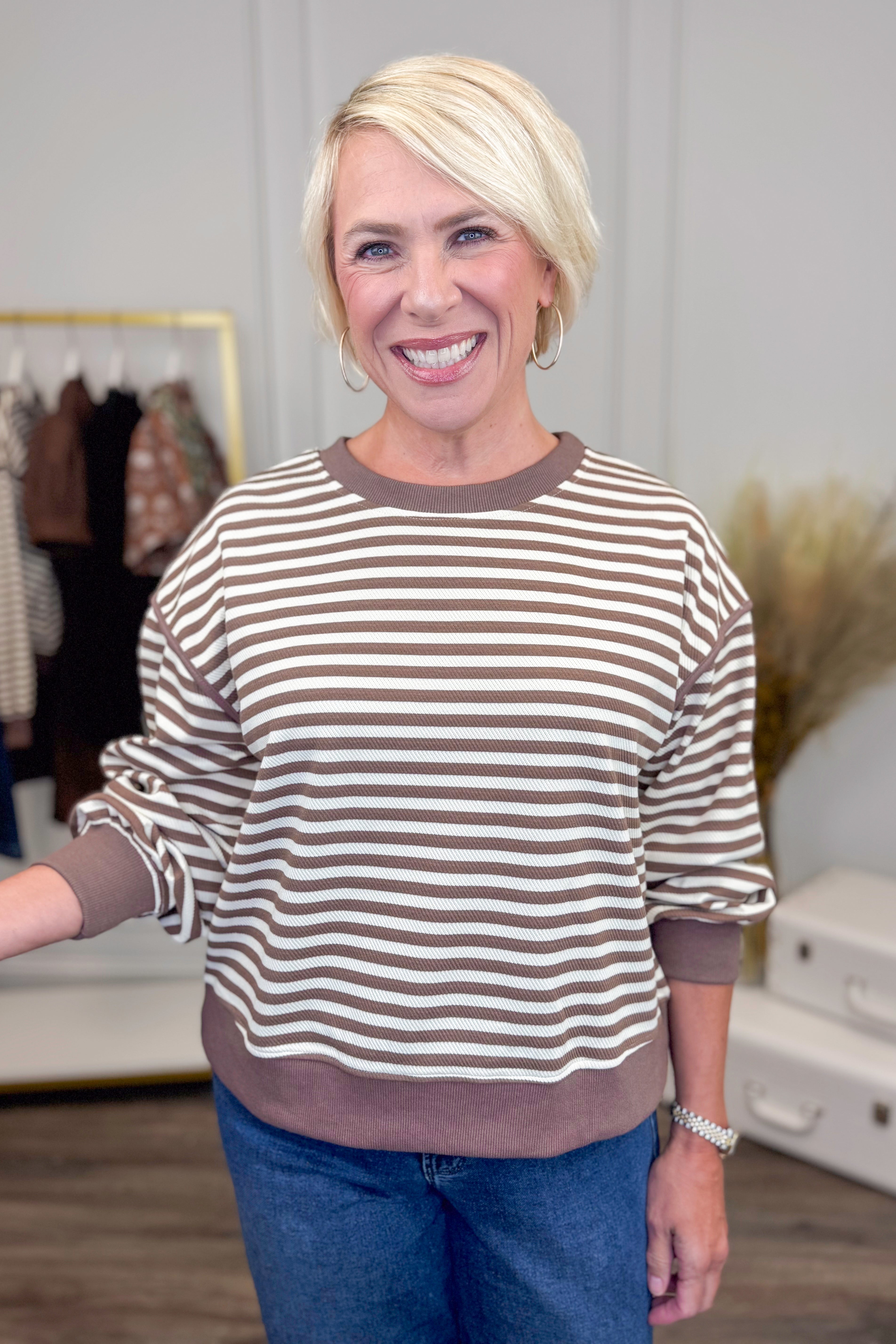 Woman wearing a striped sweater and blue jeans in an indoor setting