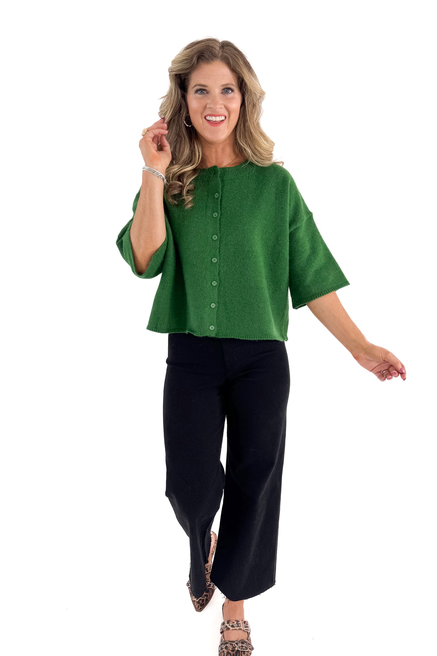 Front view of woman wearing green sweater with jeans against white studio background.