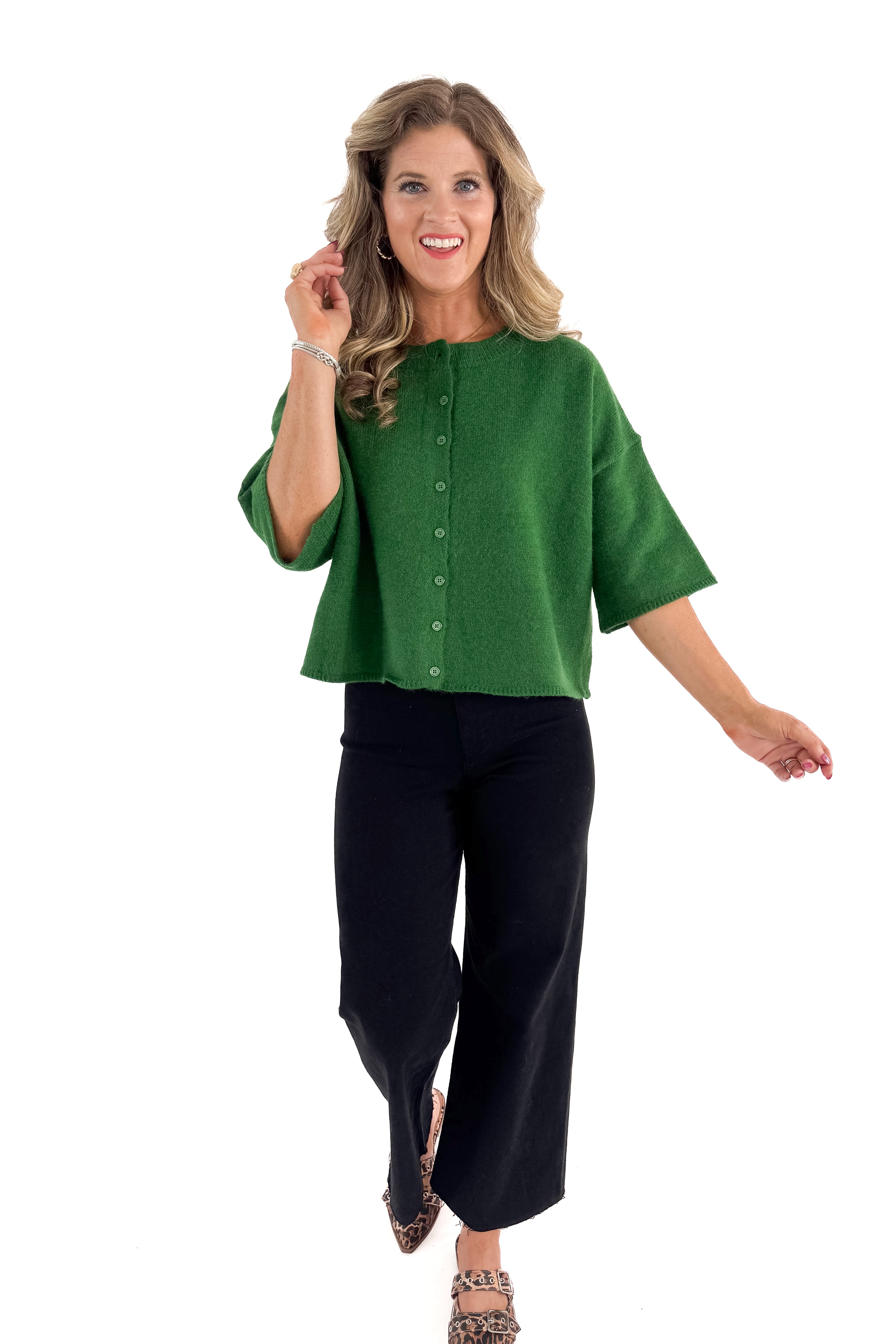 Front view of woman wearing green sweater with jeans against white studio background.