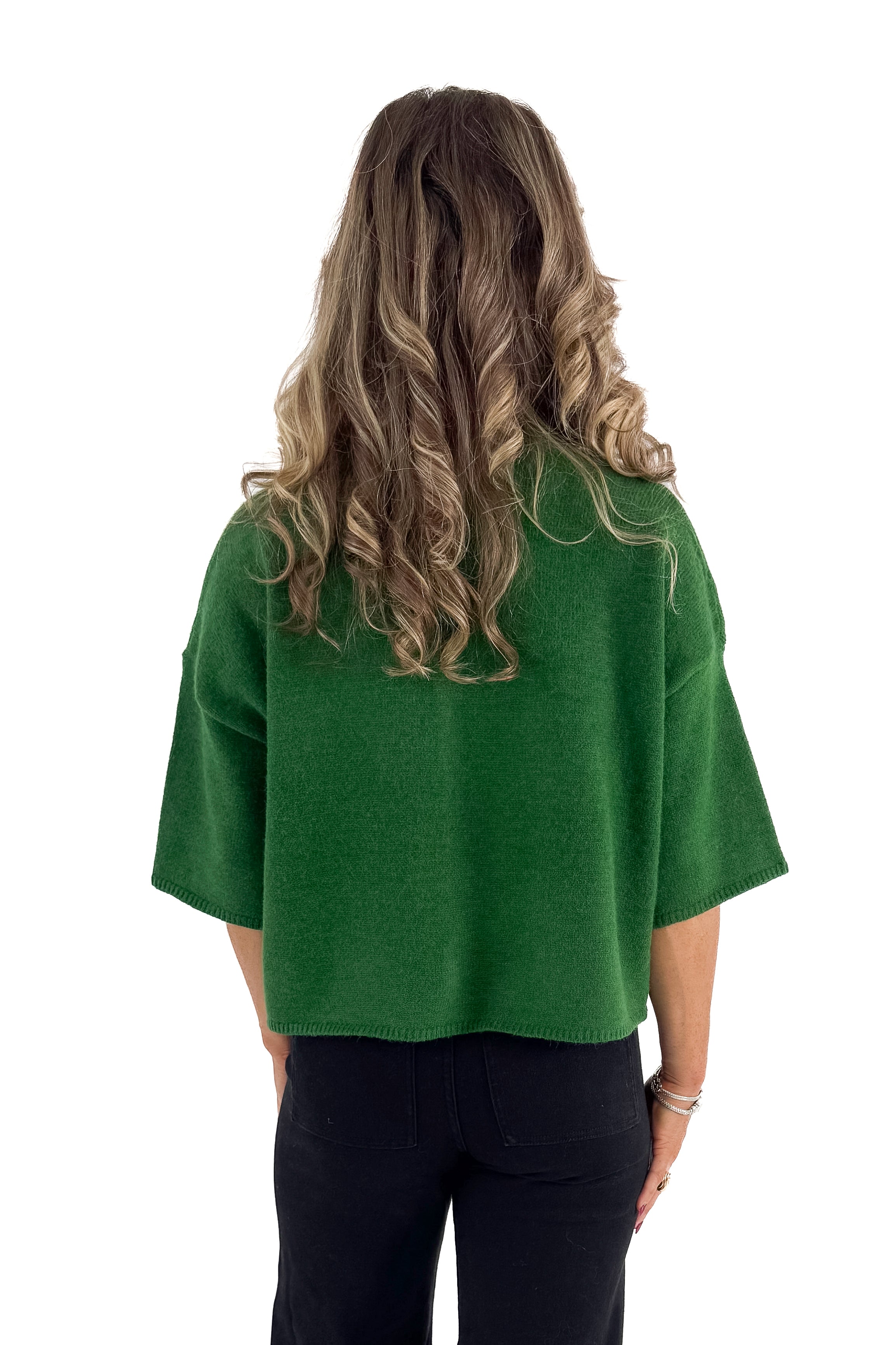 Back view of woman wearing green sweater with jeans against white studio background.