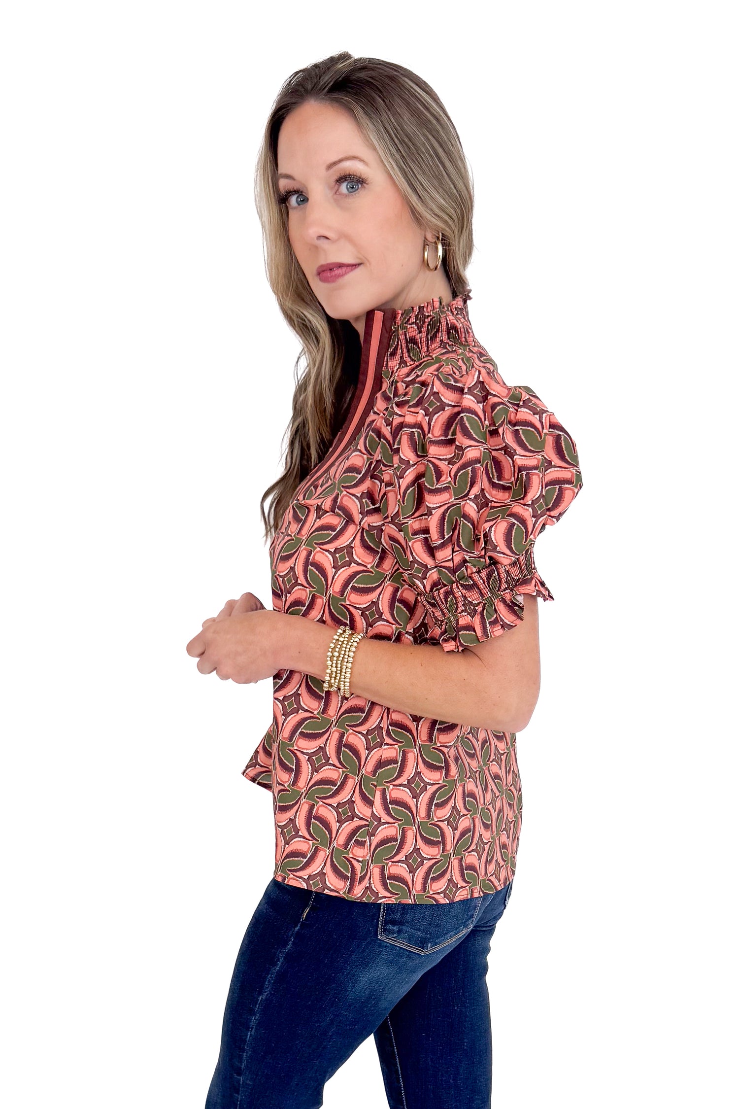 Woman wearing a patterned blouse with ruffled sleeves on a white background