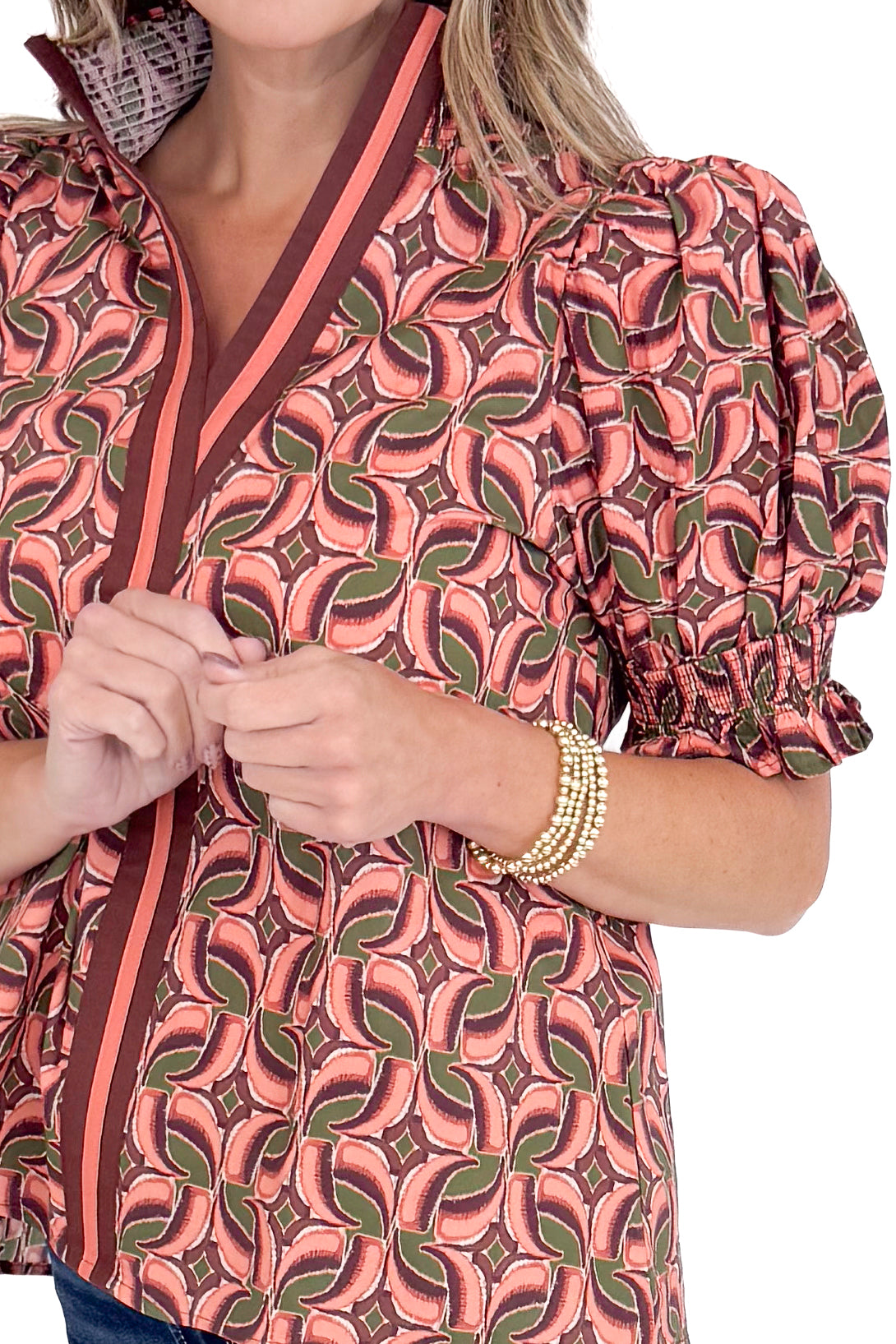 Person wearing a patterned blouse with a focus on the fabric design.