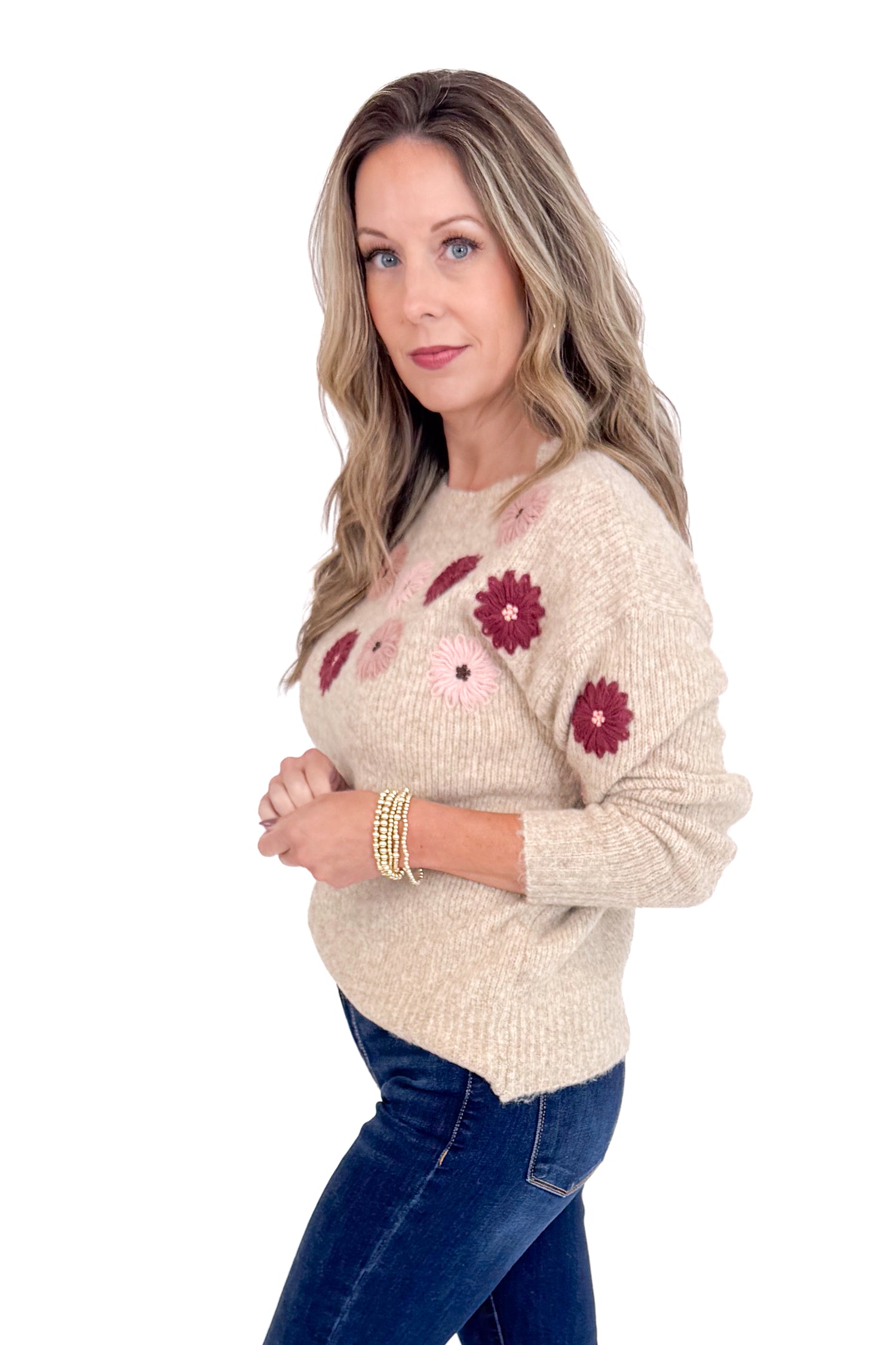 Woman wearing a beige sweater with floral patterns on a white background