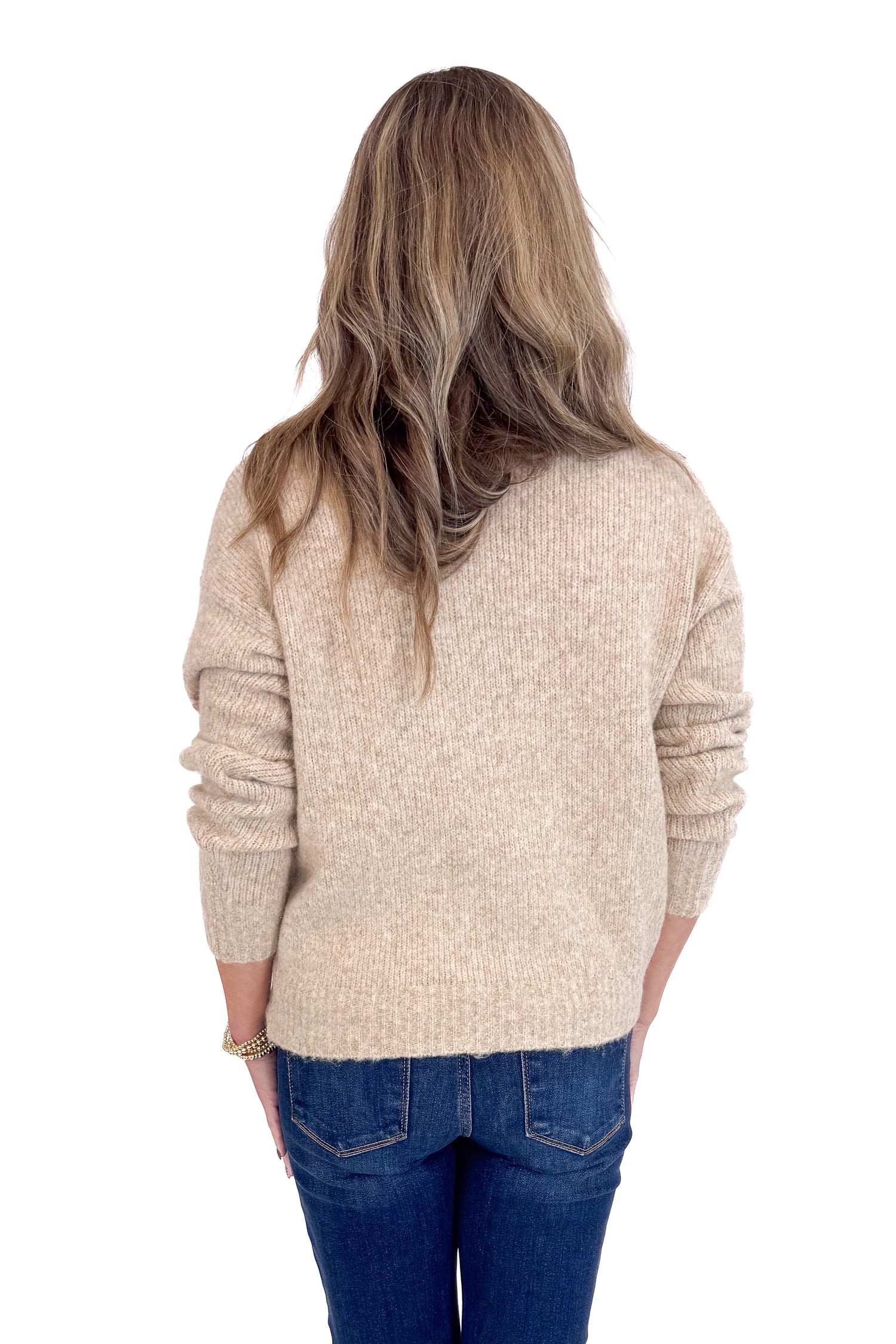 Person wearing a beige sweater and blue jeans on a white background