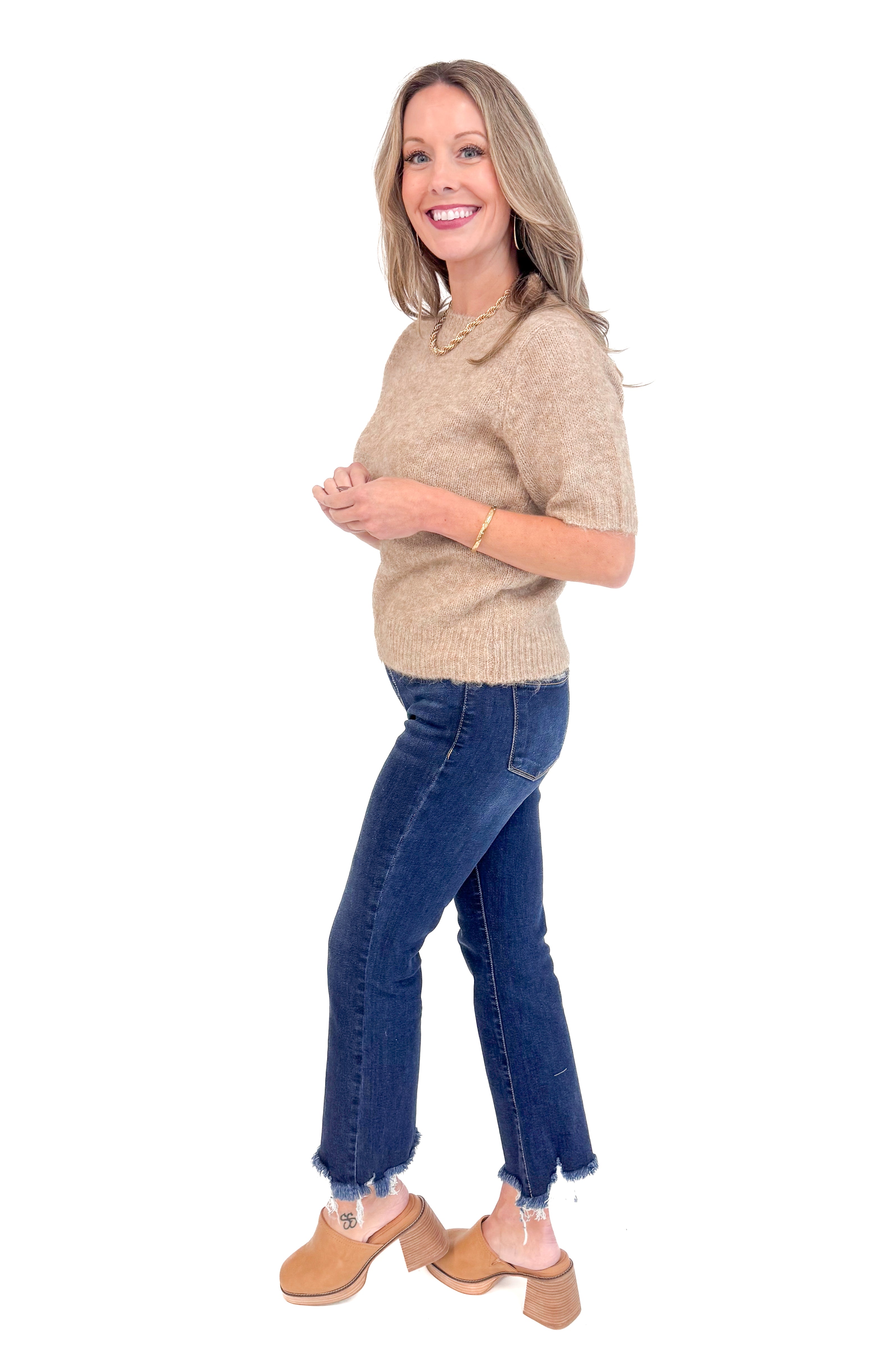 Side view of woman wearing Mocha Short Sleeve Fuzzy Sweater by Entro and blue jeans with white studio background.